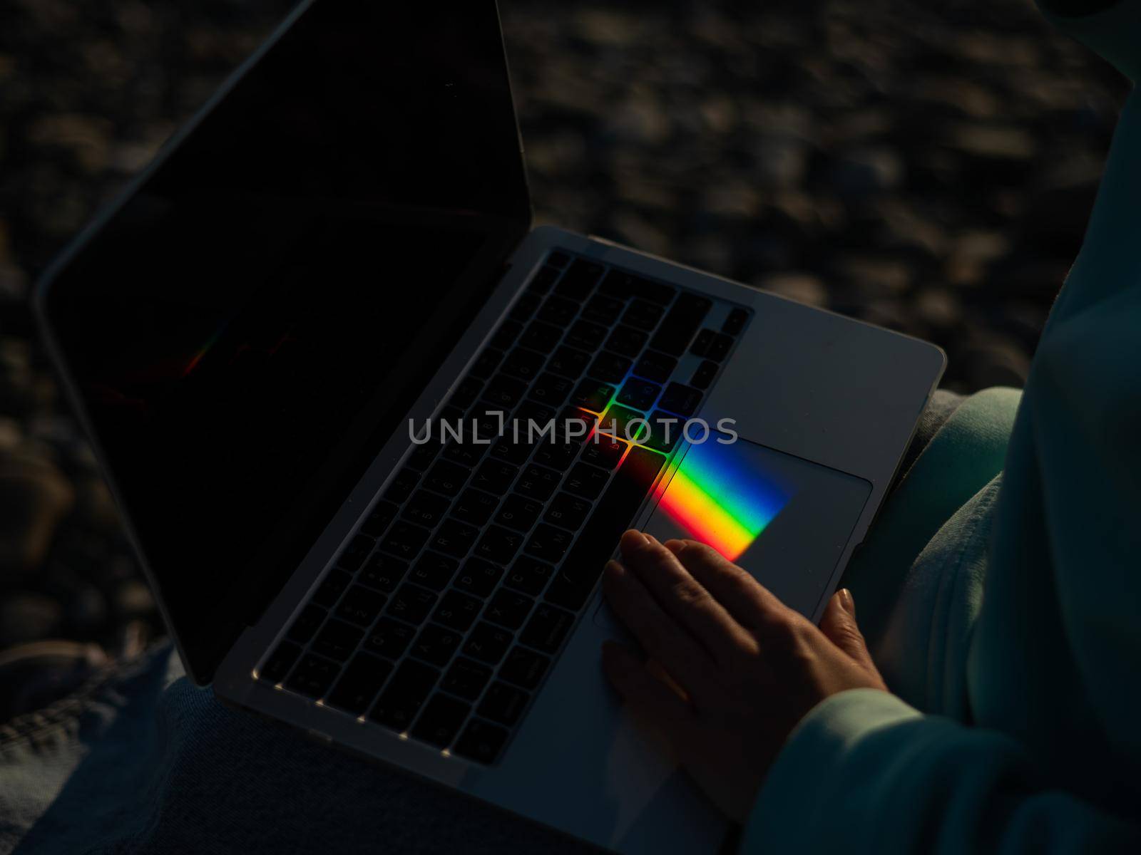 A woman is typing on a laptop. Rainbow light from a prism