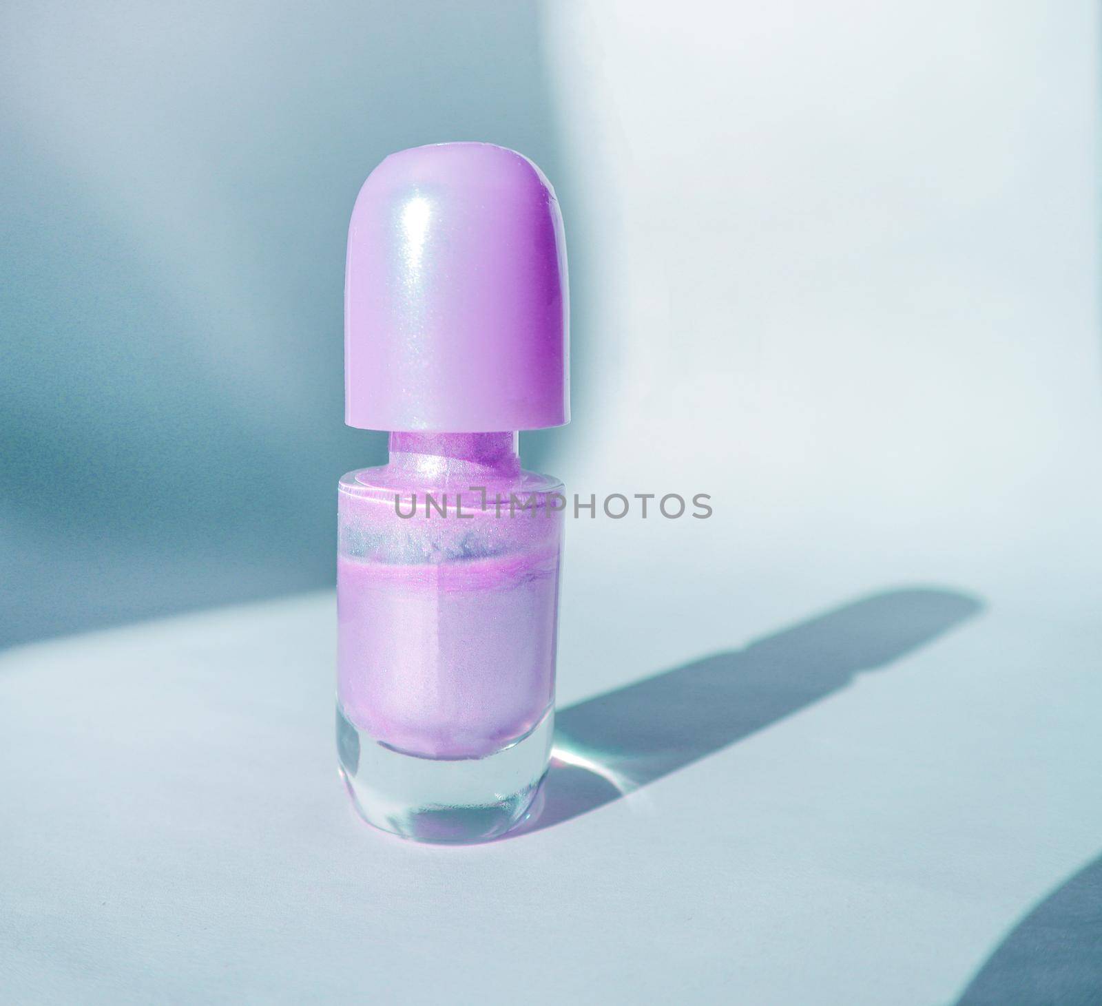 One bottle of purple nail polish on a white surface with shadow, a fashionable beauty concept by claire_lucia