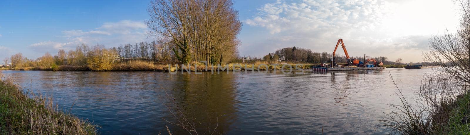 panorama of a raft with a construction crane on a river with trees