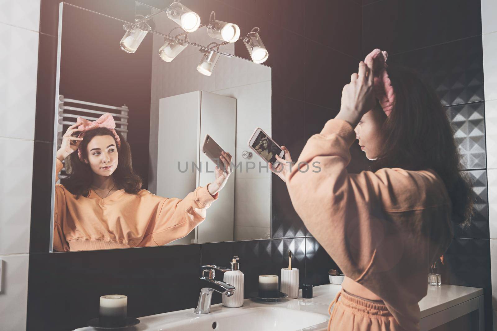 Portrait view of beautiful young woman making selfie in home bathroom. mirror face reflection. Social networks, communication.