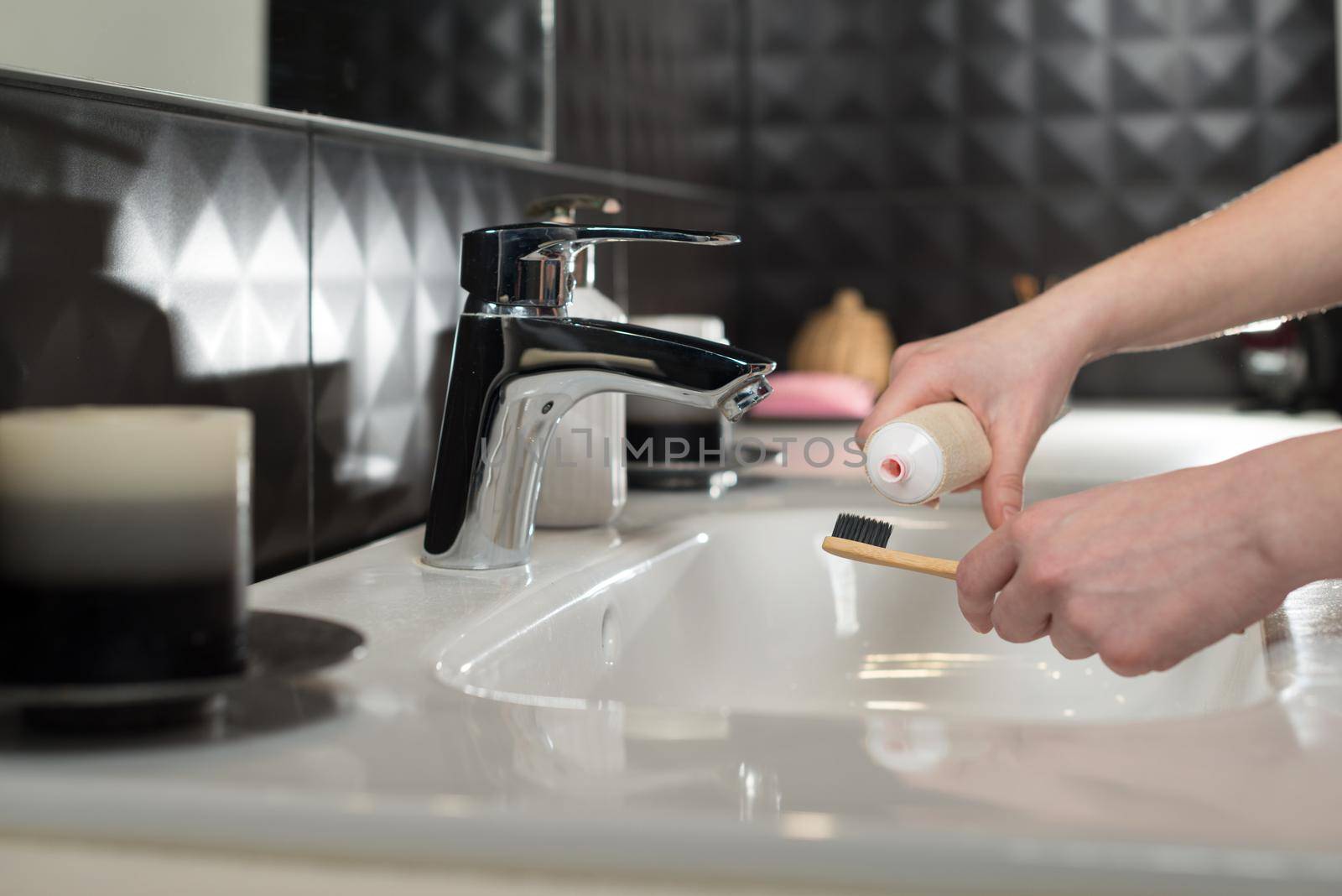 Closeup female hand is holding ecological bamboo brush with whitening toothpaste. woman is preparing going to clean teeth. Tool for oral care. Personal hygiene product concept.