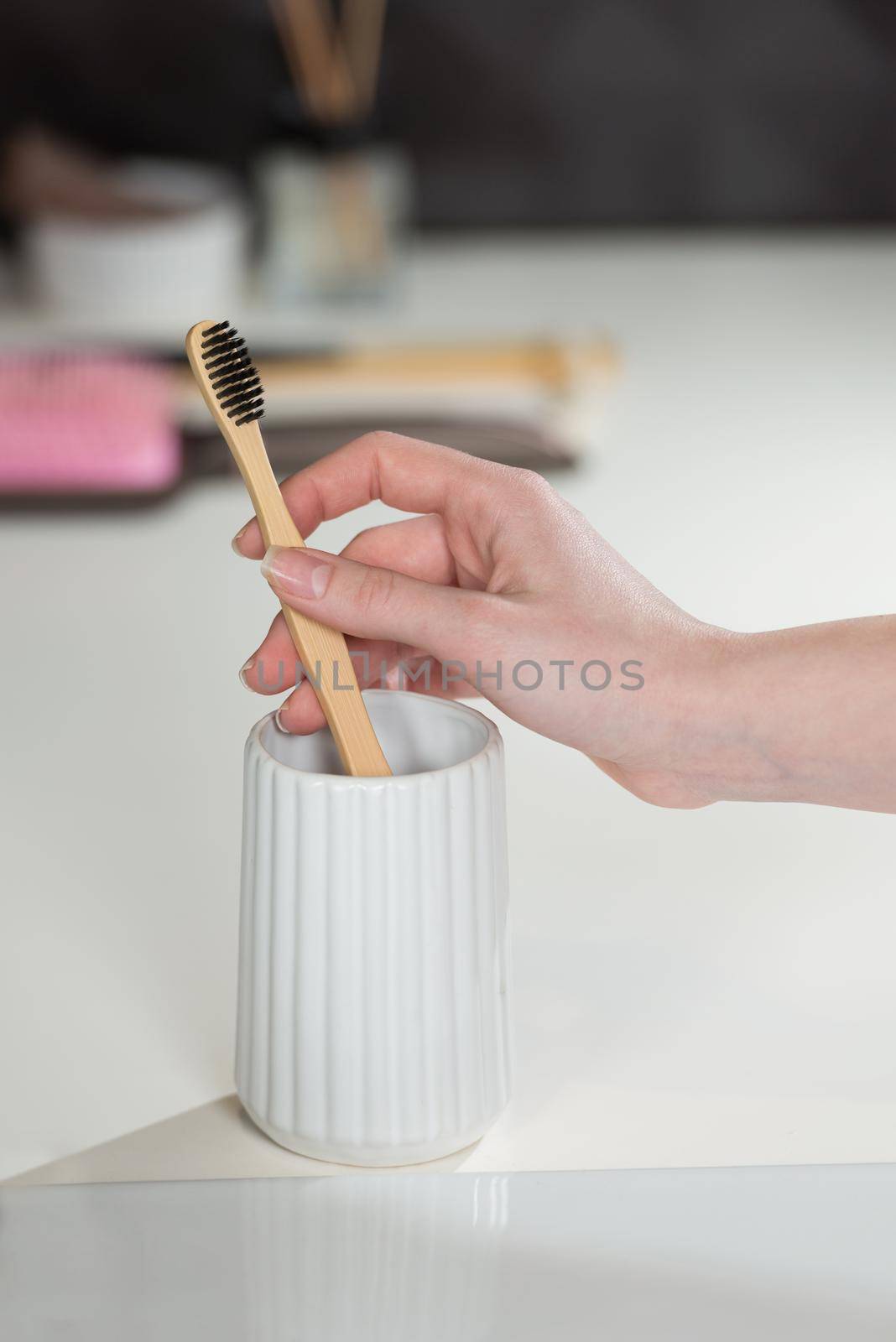 Closeup female hand is holding ecological bamboo brush. woman is preparing going to clean teeth. Tool for oral care. Personal hygiene product concept.