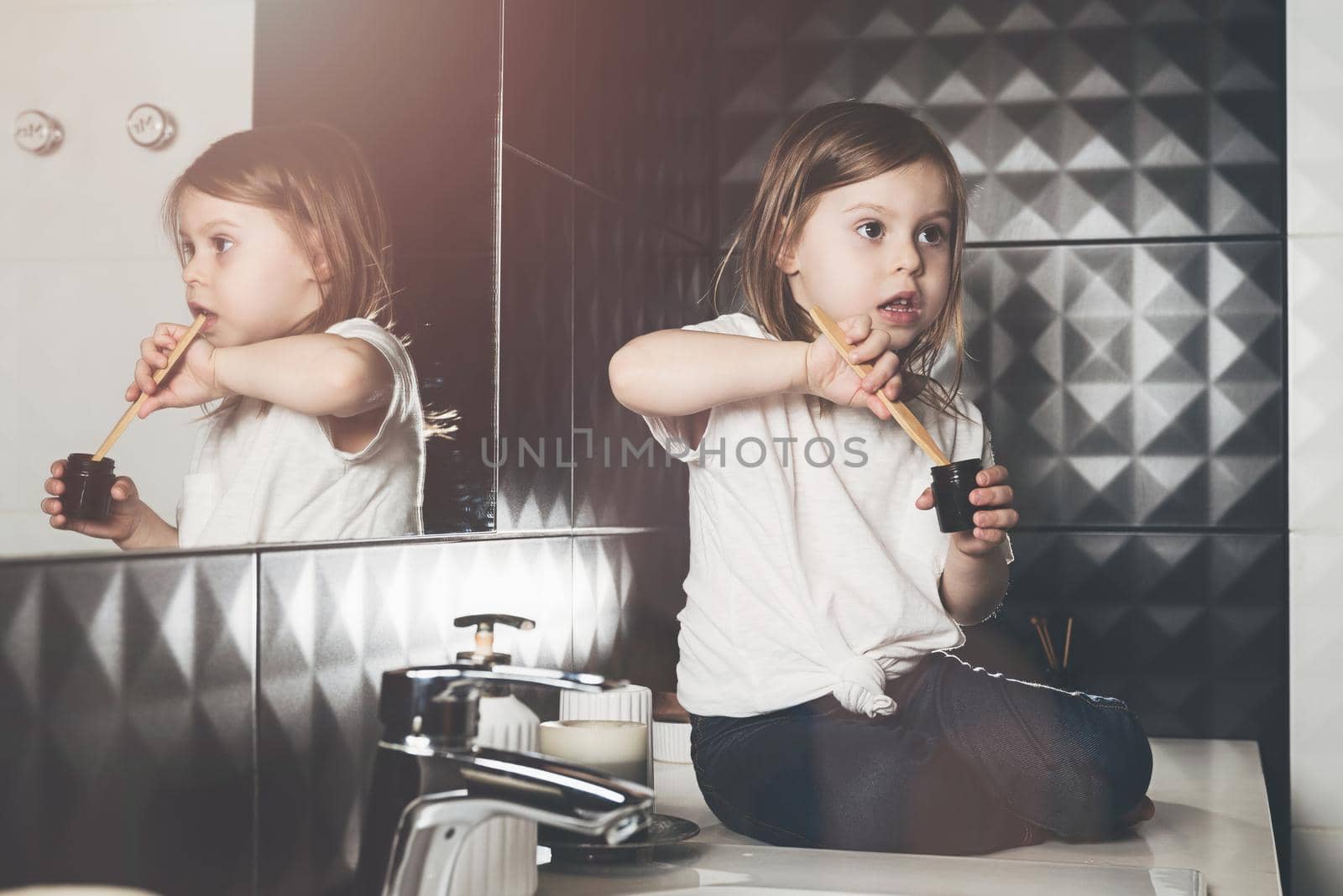 A small child in blue jeanse and white t-shirt brushes his teeth with a bamboo toothbrush. by Ashtray25