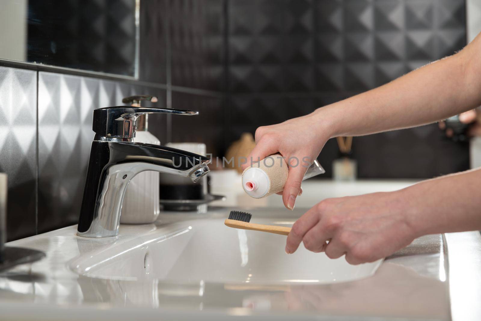 Closeup female hand is holding ecological bamboo brush with whitening toothpaste. woman is preparing going to clean teeth. Tool for oral care. Personal hygiene product concept.