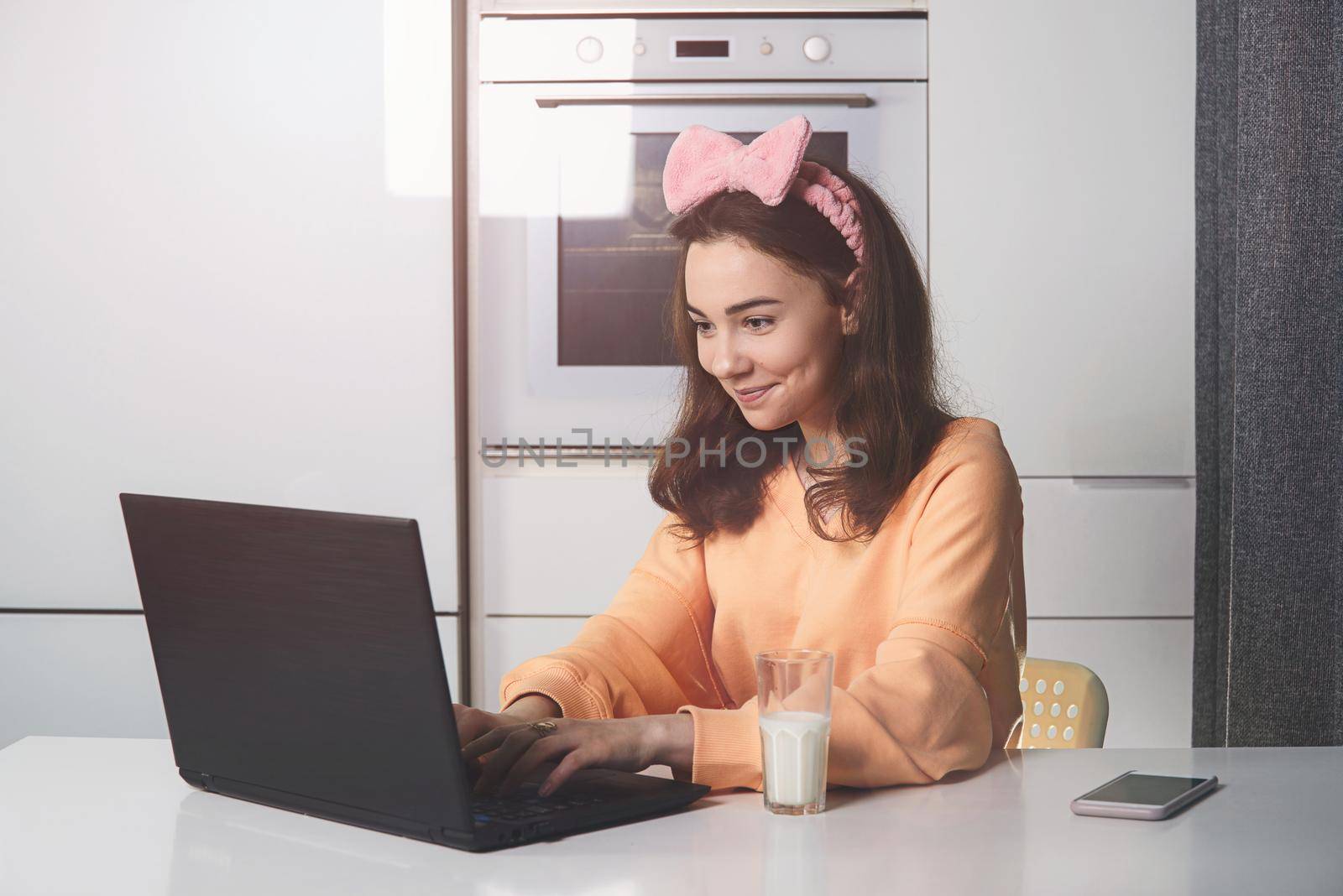 Young woman in a kitchen catching up and having fun while studying on a laptop computer. Distance Learning. by Ashtray25