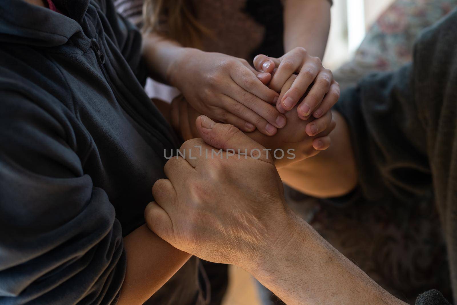 A hand of a granddaughter is holding a wrinkled hand of an old man symbolizing care, attention and unconditional love