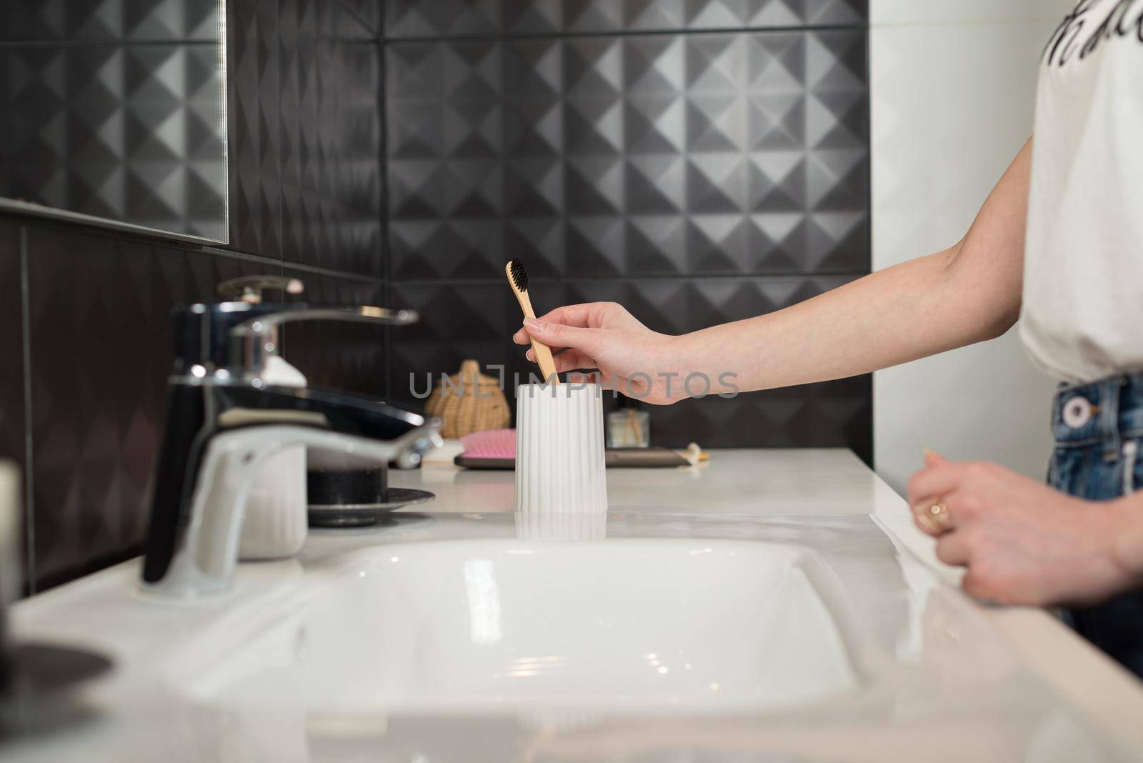 Closeup female hand is holding ecological bamboo brush. woman is preparing going to clean teeth. Tool for oral care. Personal hygiene product concept.