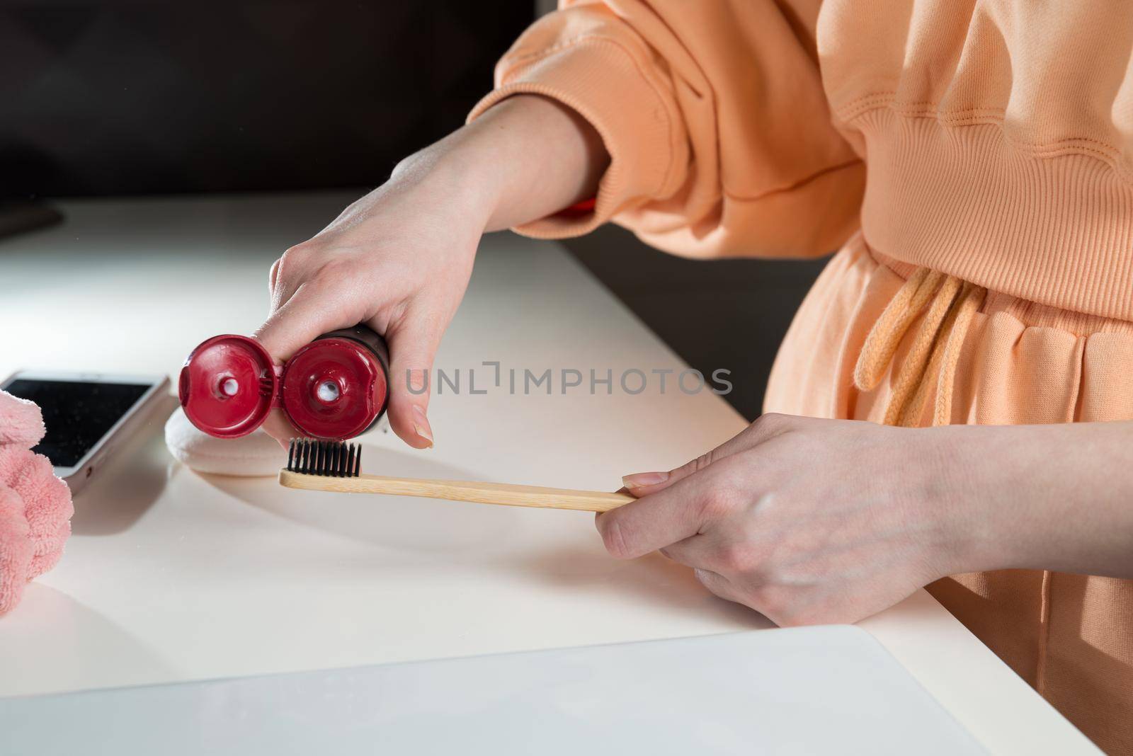 Closeup female hand is holding ecological bamboo brush with whitening toothpaste. woman is preparing going to clean teeth. Tool for oral care. by Ashtray25