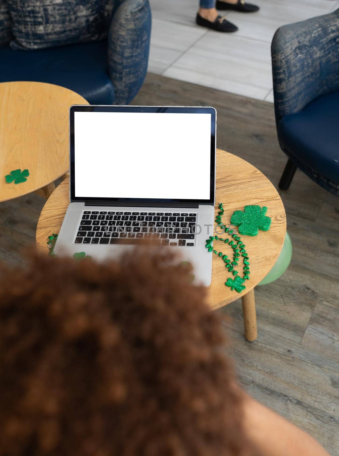 Mixed race woman celebrating st patrick's day on laptop video call with copy space on screen. fun during celebration of the irish patron saint's day.