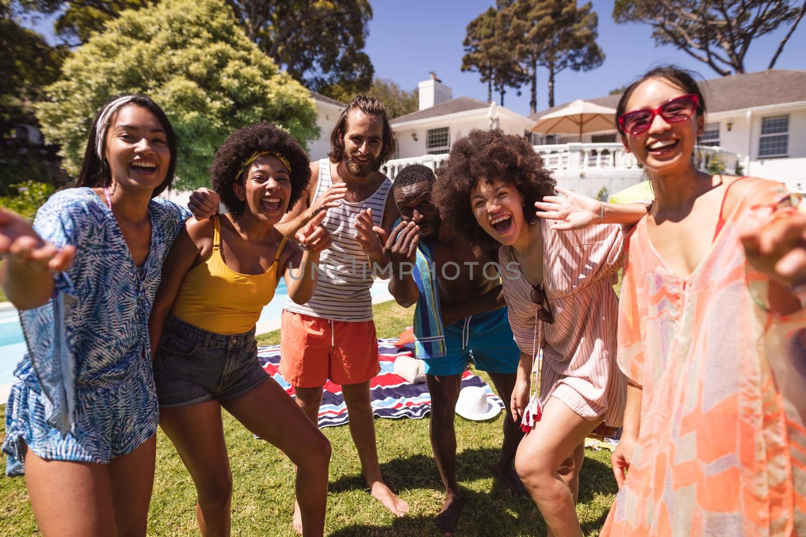 Diverse group of friends having fun and smiling at a pool party. Hanging out and relaxing outdoors in summer.