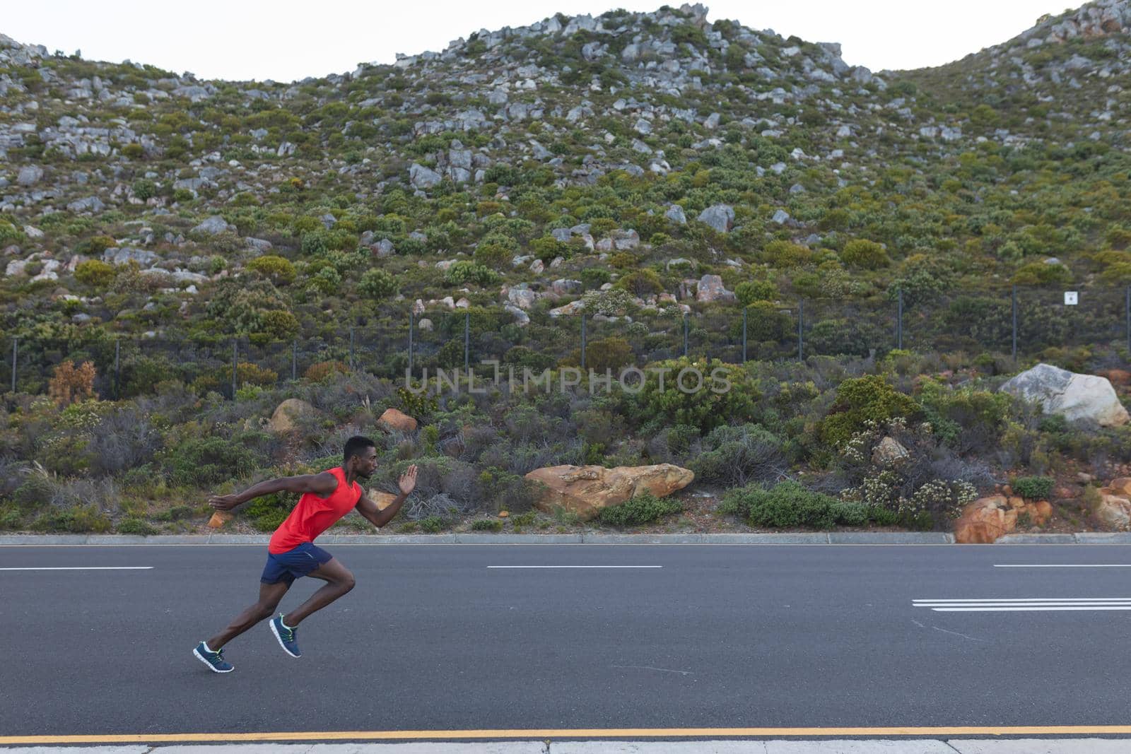 Fit african american man in sportswear running on a coastal road by Wavebreakmedia