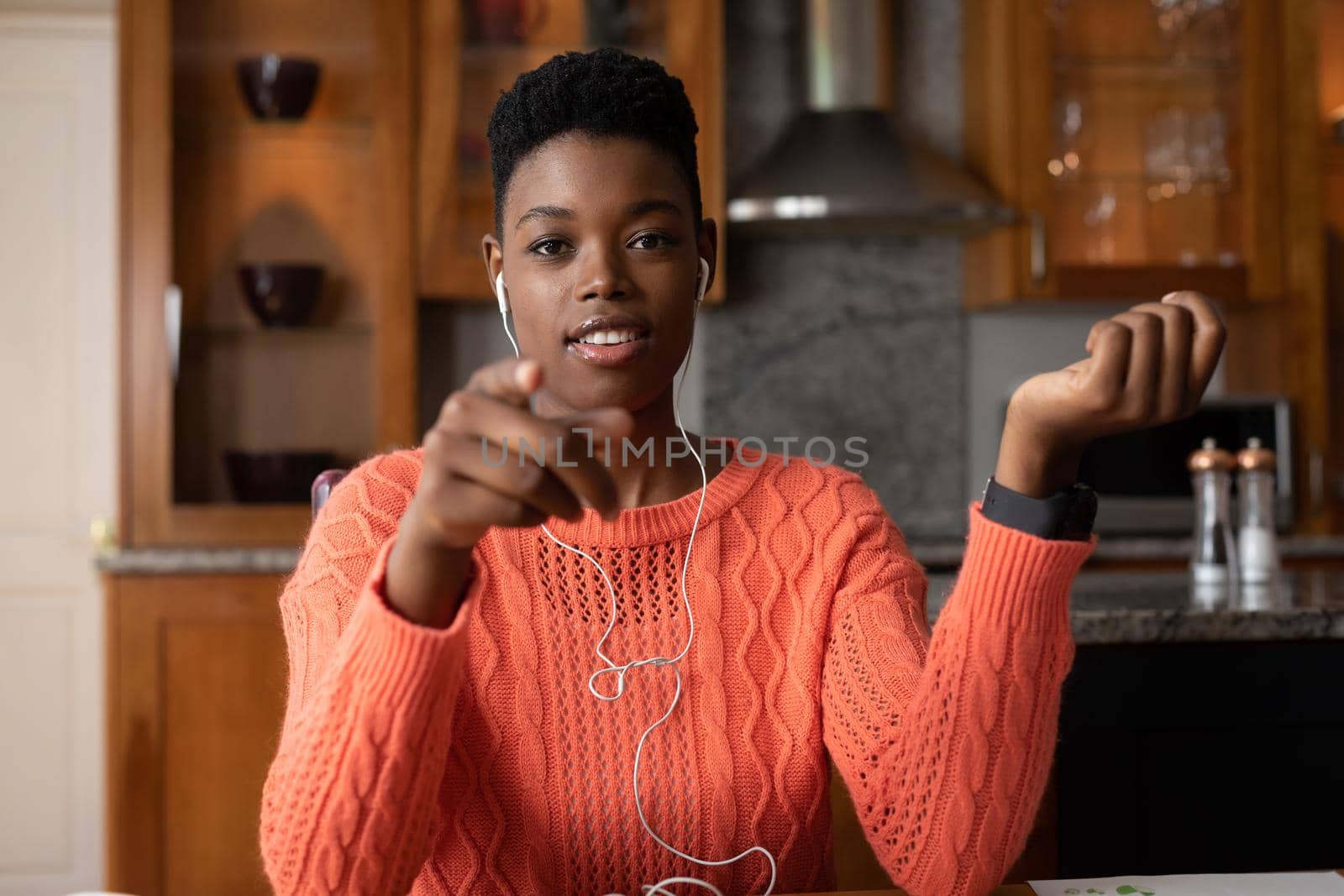 Portrait of african american woman wearing earphones having a videocall while working from home. staying at home in self isolation in quarantine lockdown