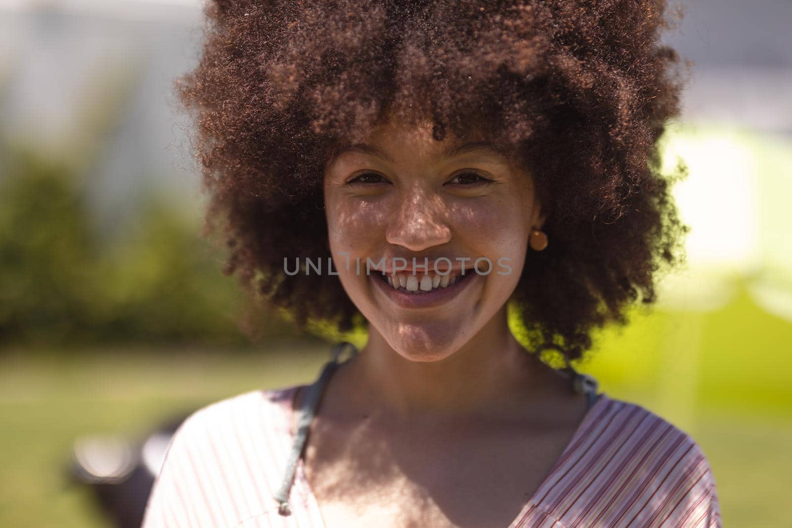 Portrait of mixed race woman looking at camera and smiling. Hanging out and relaxing outdoors in summer.