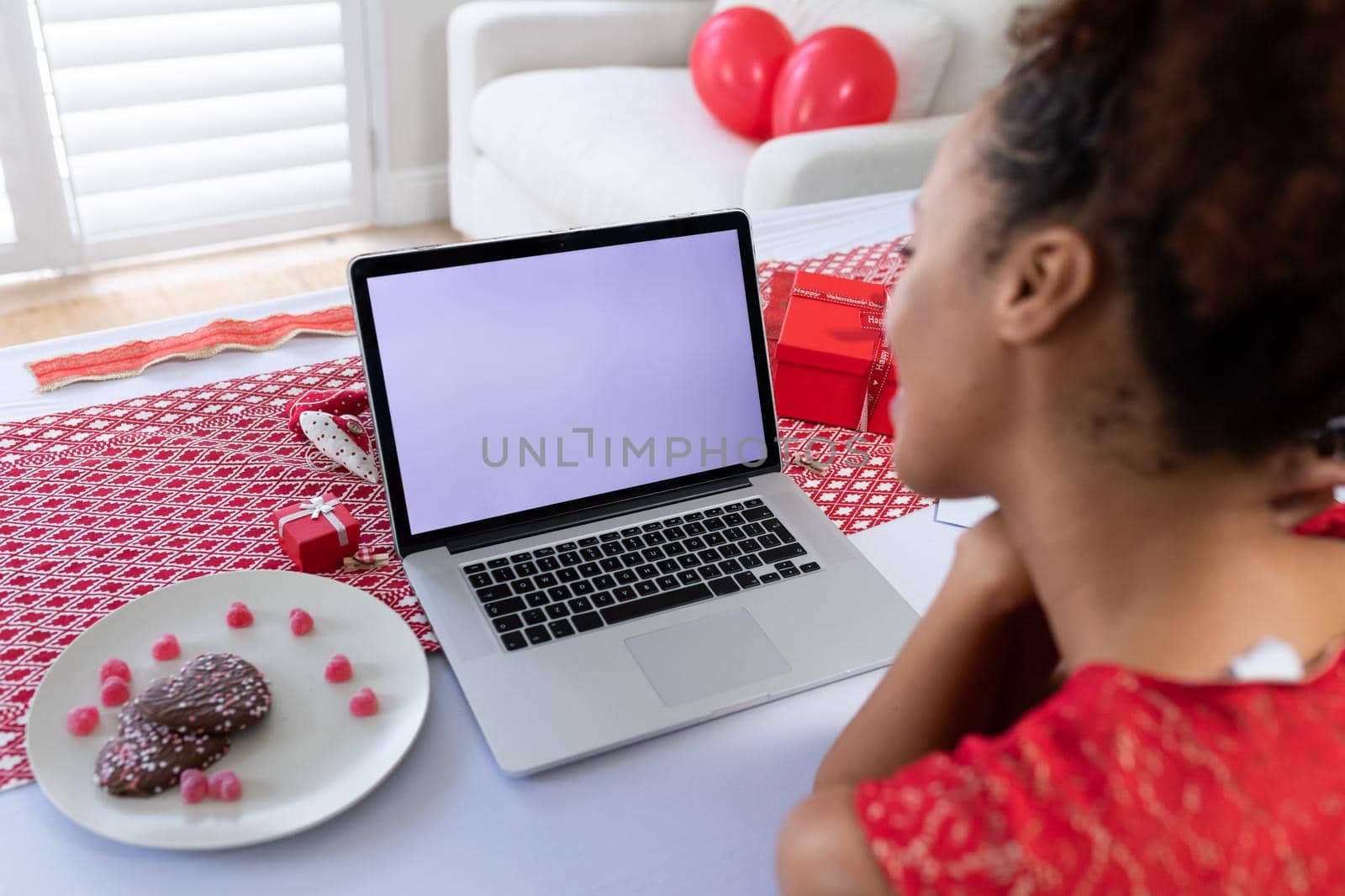 African american woman having a videocall on laptop at home. distant celebration of valentines day online and dating concept