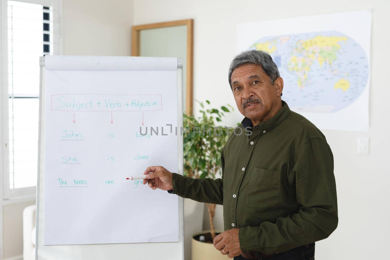 Mixed race male english teacher standing at a whiteboard giving an online lesson to camera. education at home in self isolation during quarantine lockdown.