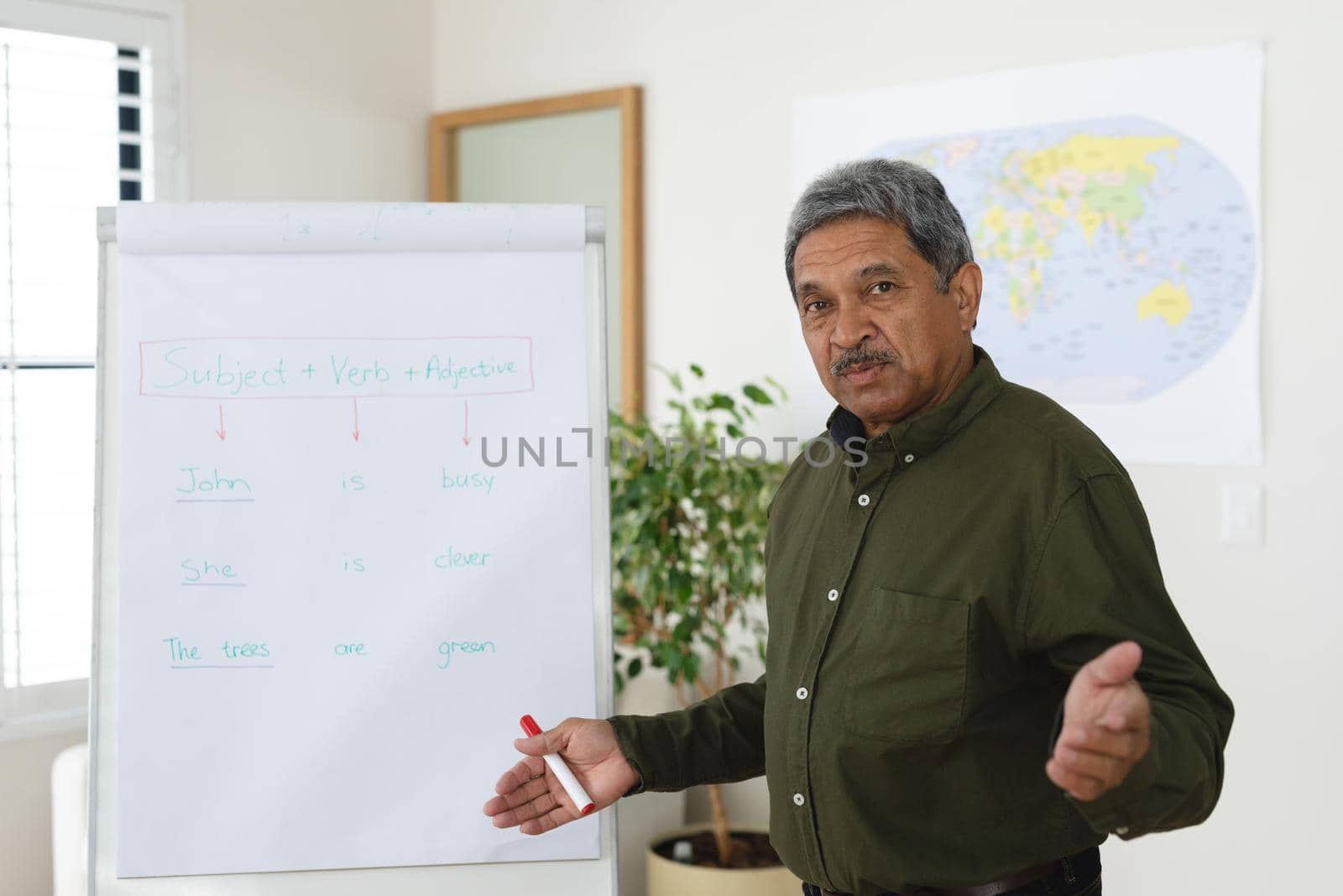 Mixed race male english teacher standing at a whiteboard giving an online lesson to camera. education at home in self isolation during quarantine lockdown.