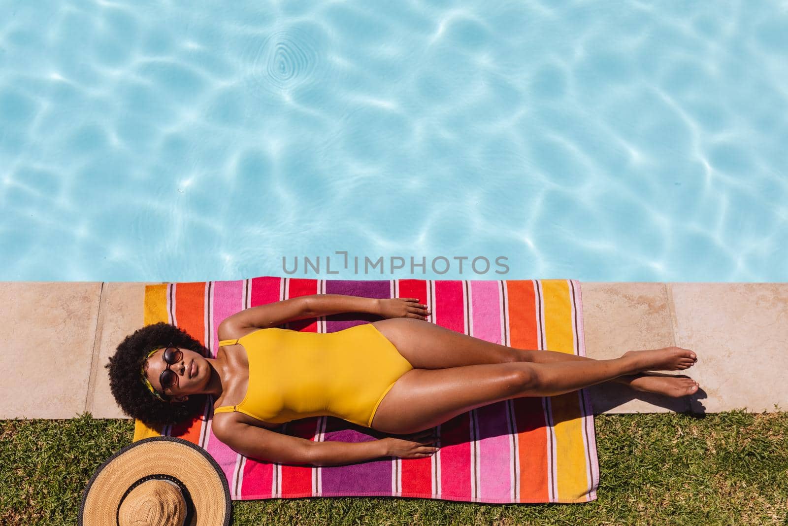 Mixed race woman sunbathing by pool on a sunny day by Wavebreakmedia