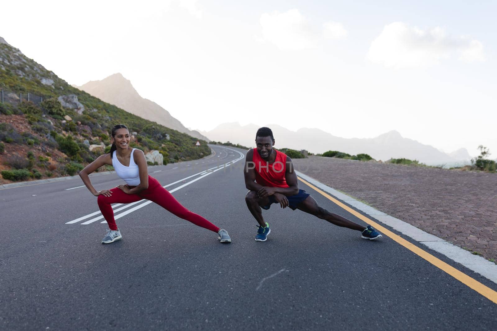 Fit african american couple in sportswear stretching on a coastal road by Wavebreakmedia
