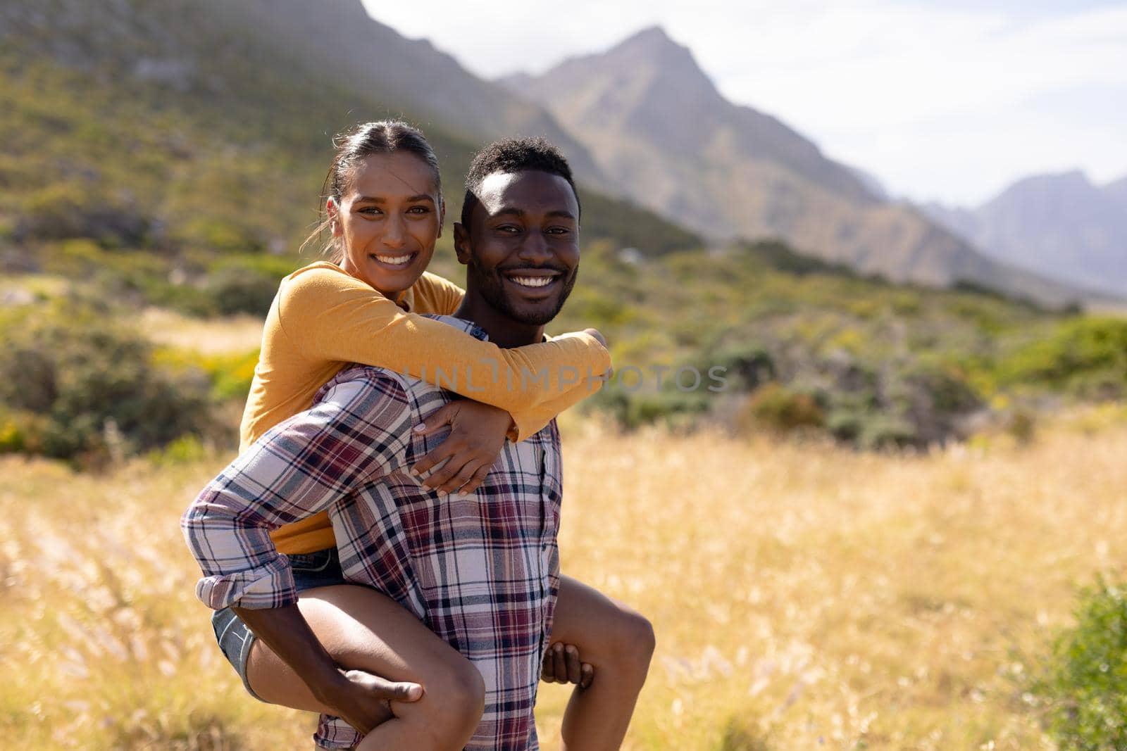 Fit african american couple resting and embracing in mountain countryside. looking at the camera and smiiling. healthy lifestyle, exercising in nature.