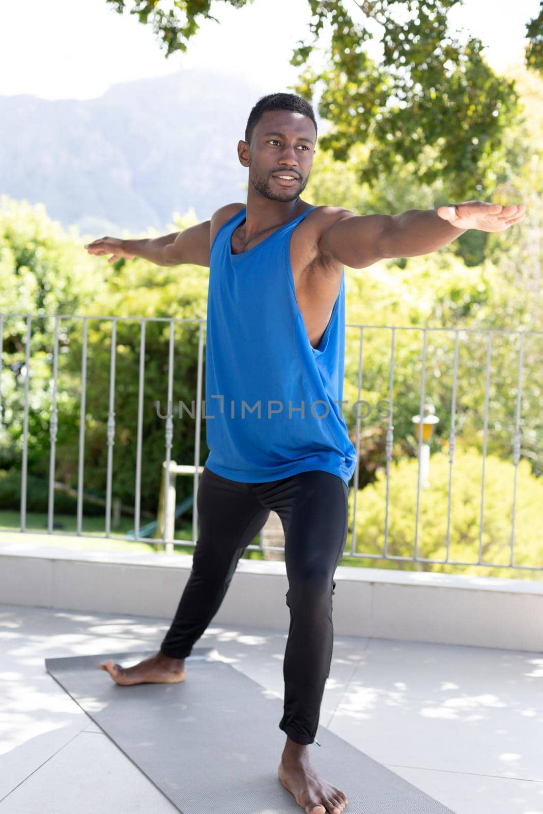 African american man exercising practicing yoga on sunny garden terrace. staying at home in isolation during quarantine lockdown.