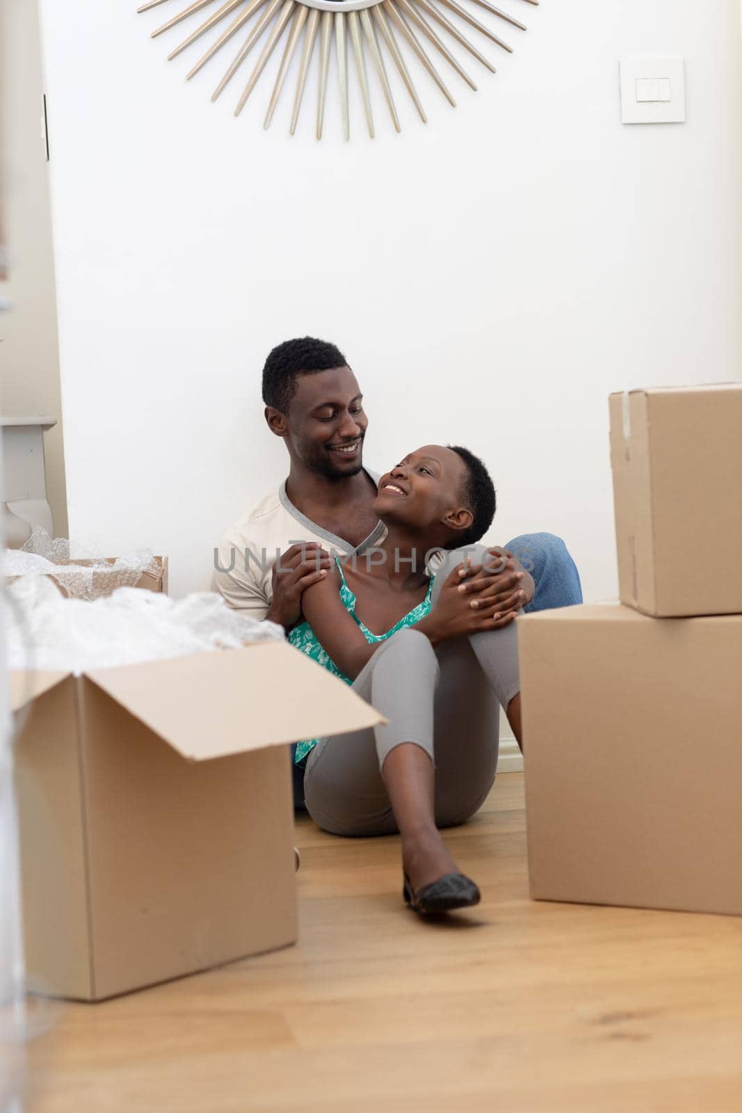 African american couple moving house unpacking sitting on floor and embracing. staying at home in isolation during quarantine lockdown.