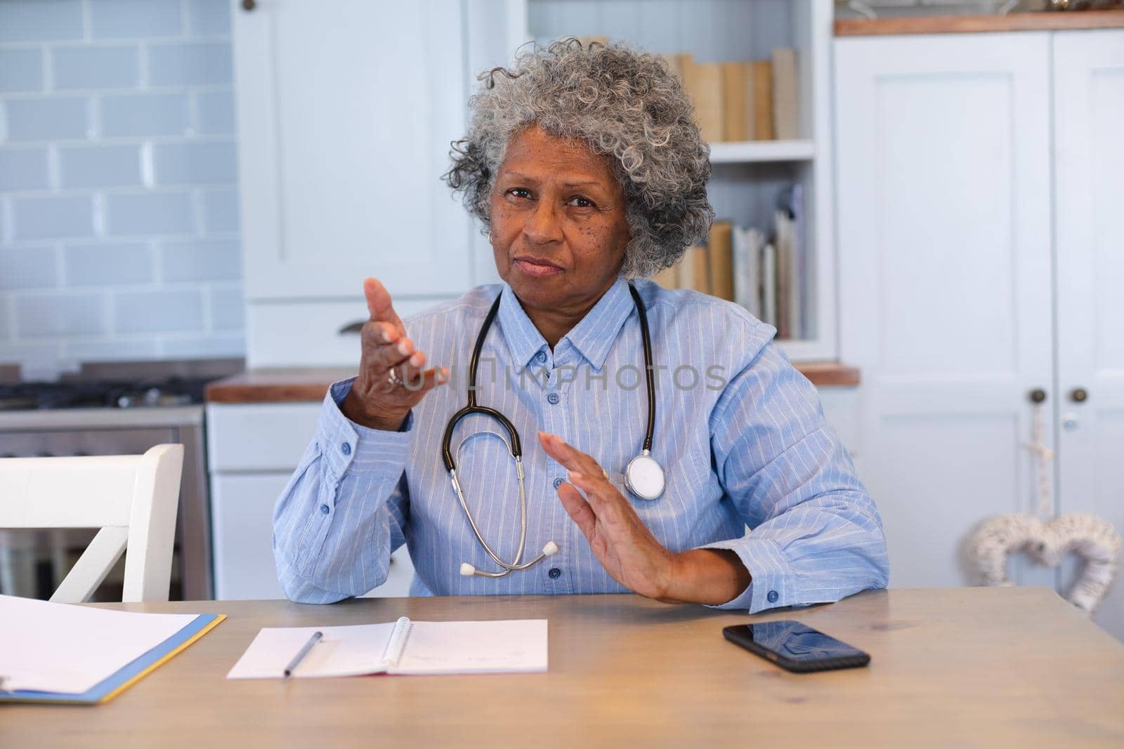 Portrait of african american senior female doctor talking looking at the camera at home by Wavebreakmedia