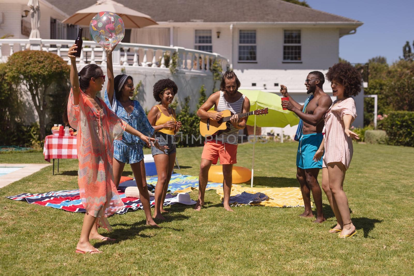 Diverse group of friends dancing and smiling at a pool party by Wavebreakmedia