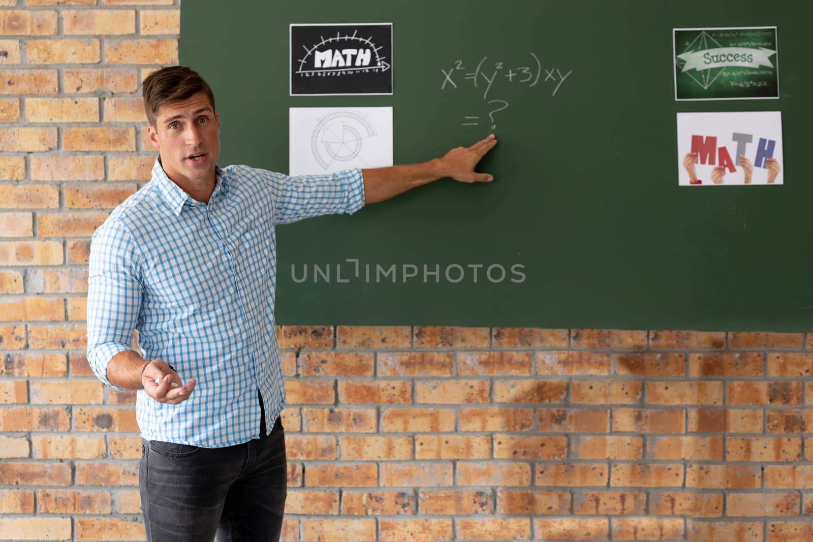 Portrait of male caucasian teacher teaching mathematics in the classroom at school by Wavebreakmedia