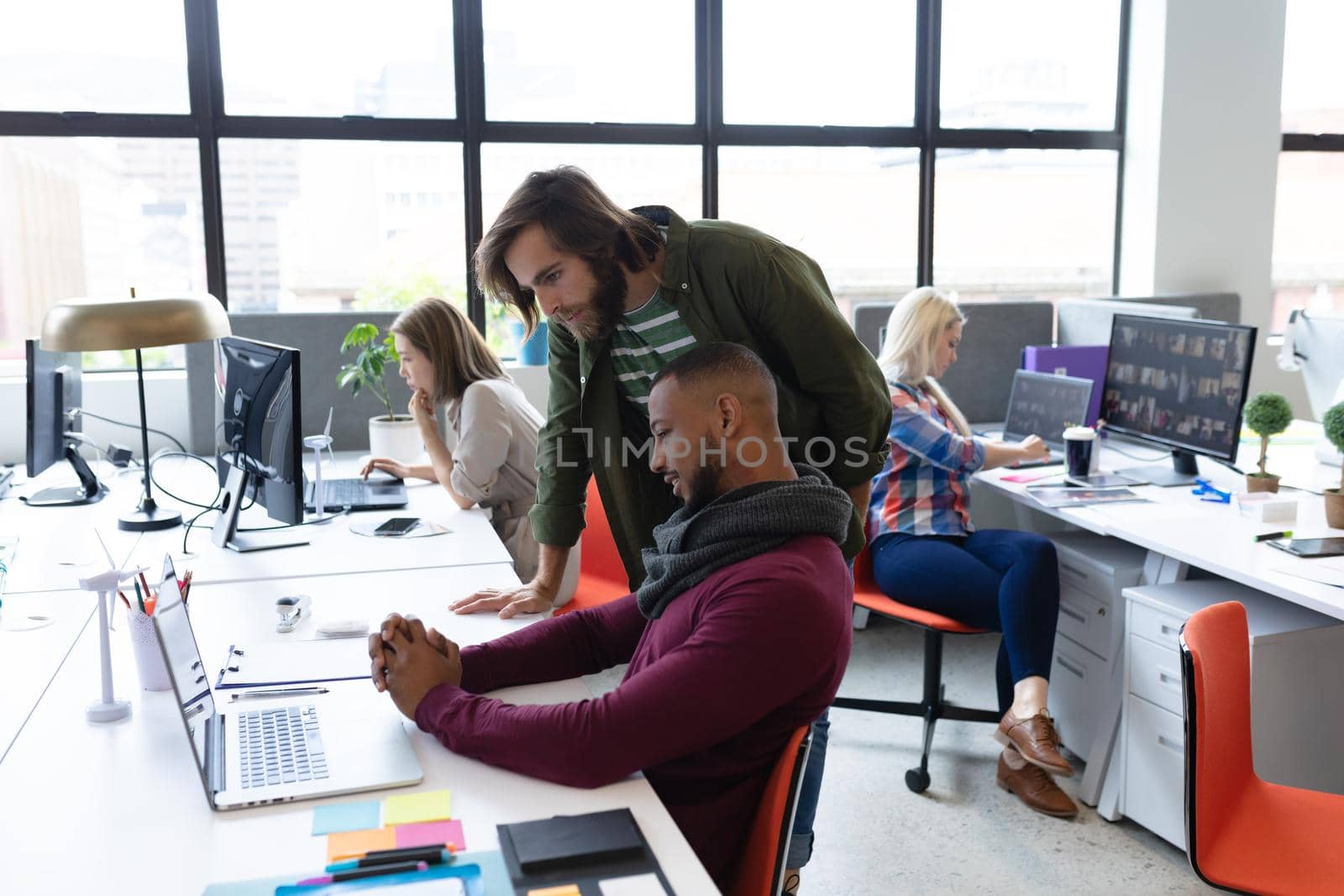 Two diverse businessmen working in creative office. men using computer and discussing work. business people and work colleagues at a busy creative office.