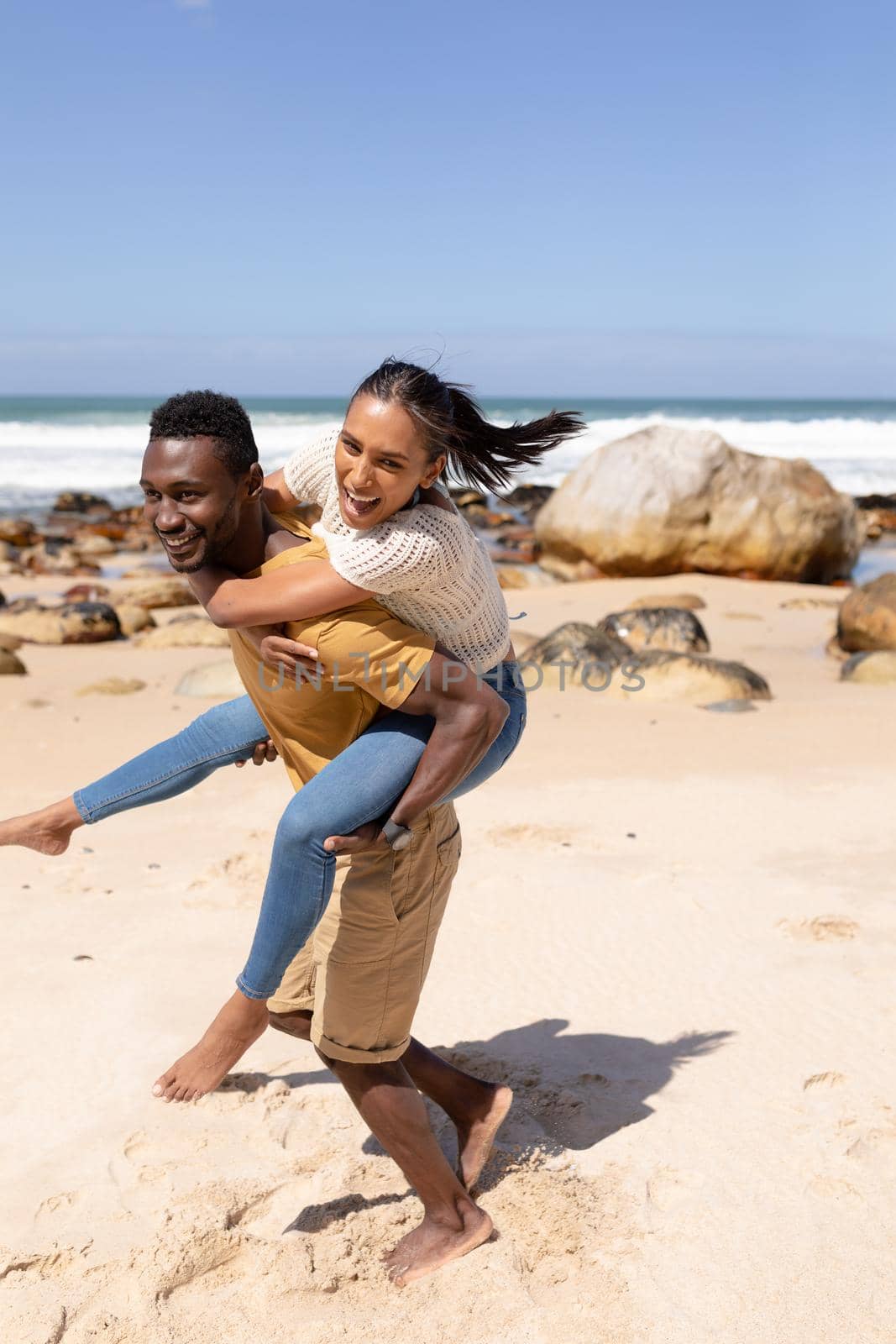 African american couple piggybacking on a beach by the sea by Wavebreakmedia