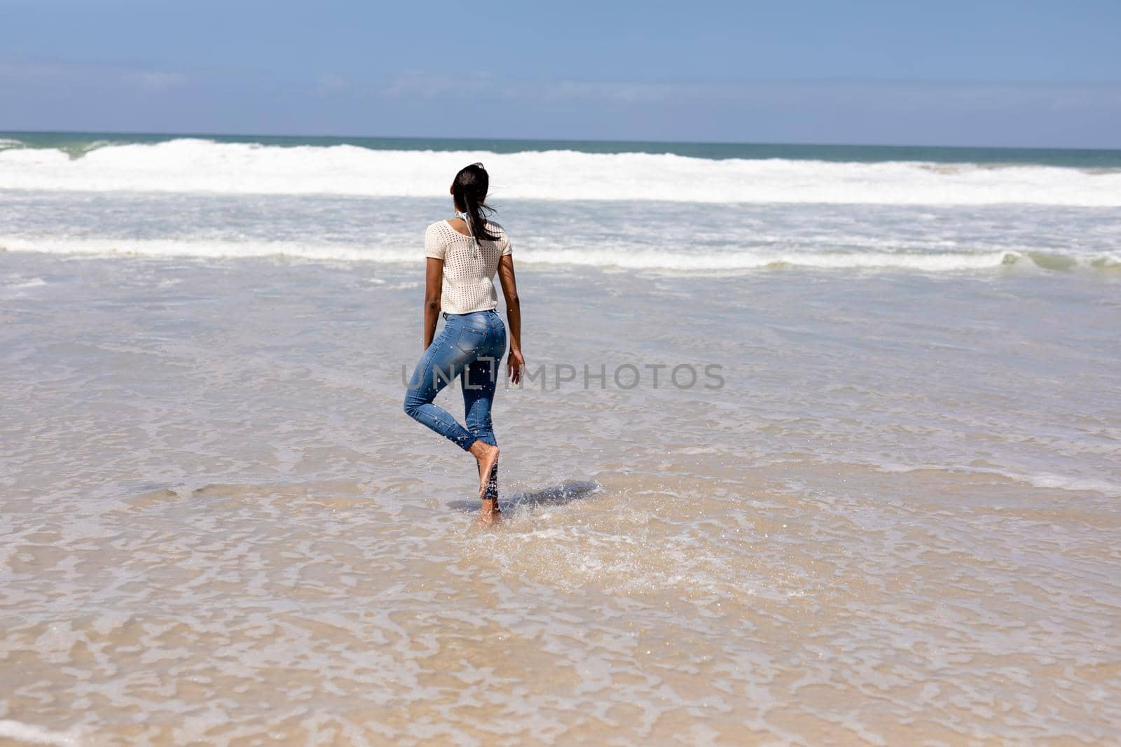 African american woman walking on a beach by the sea. healthy lifestyle, leisure in nature.