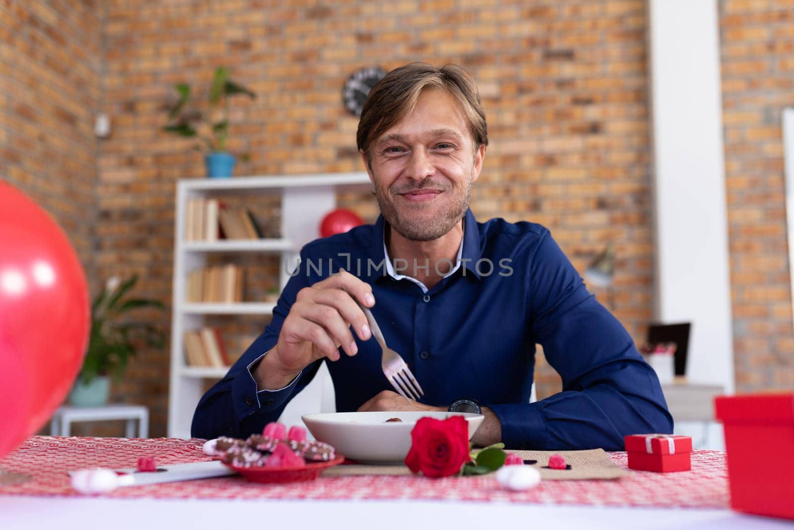 Smiling caucasian man making video call sitting a table eating. online communication during quarantine lockdown