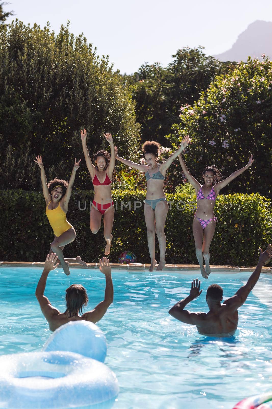 Diverse group of female friends jumping into water at a pool party by Wavebreakmedia