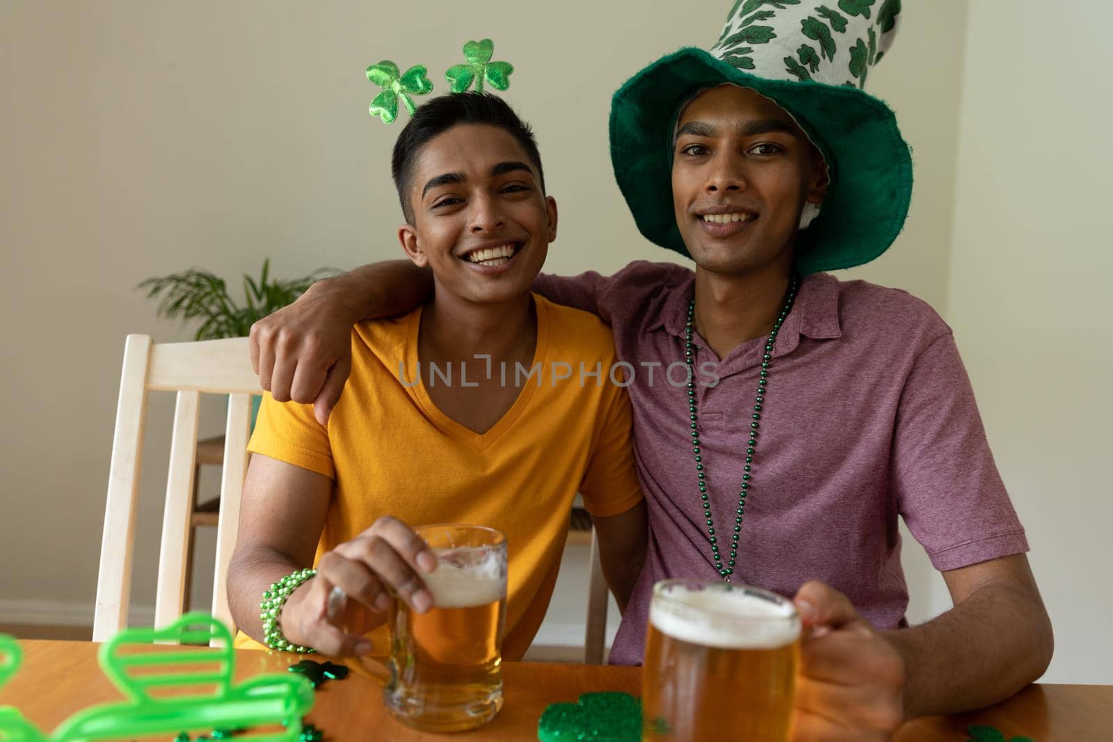 Portrait of diverse gay male couple wearing st patrick's day costumes and holding glasses of beer by Wavebreakmedia