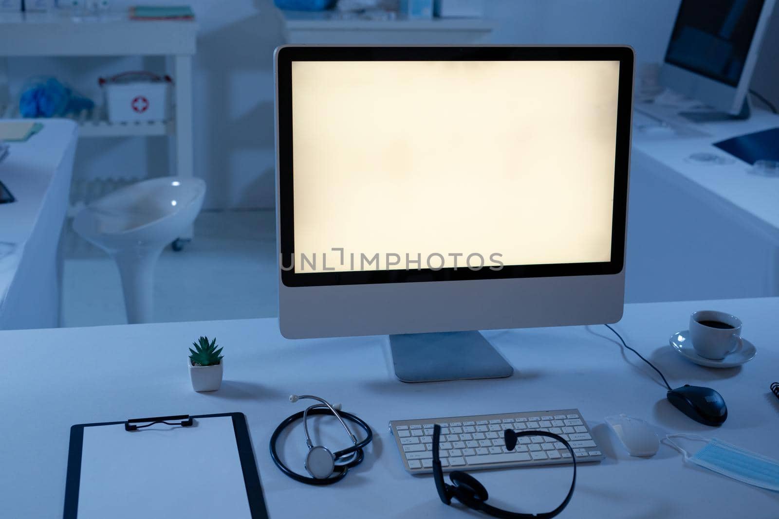 Desktop computer with illuminated screen at workstation in doctors surgery. telemedicine online healthcare during quarantine lockdown.