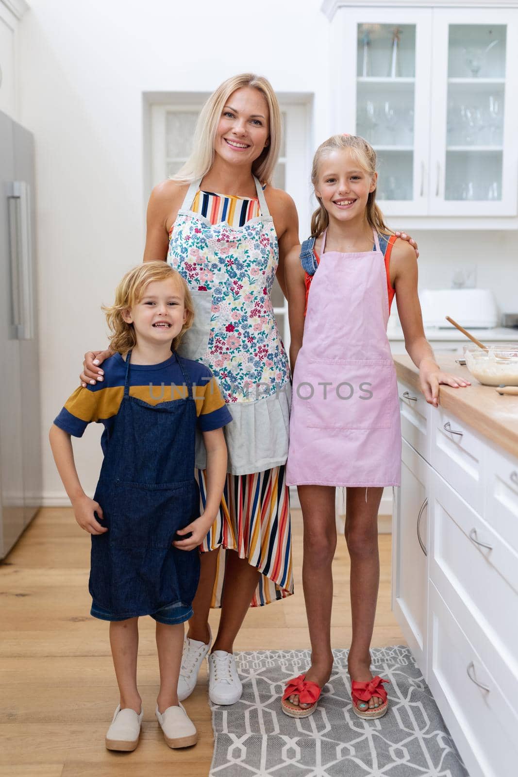 Caucasian mother standing in kitchen with daughter and son in aprons prepared for cooking. . staying at home in isolation during quarantine lockdown.
