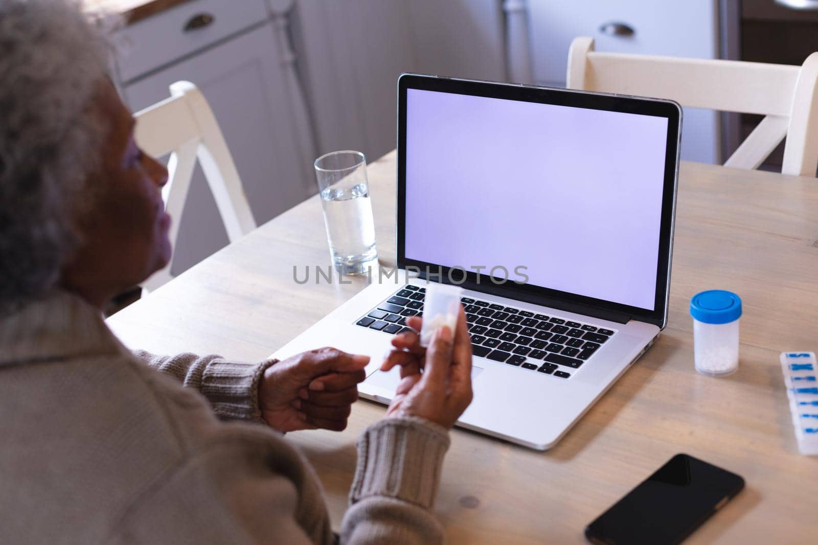 African american woman holding medication container having a video call on laptop with copy space by Wavebreakmedia