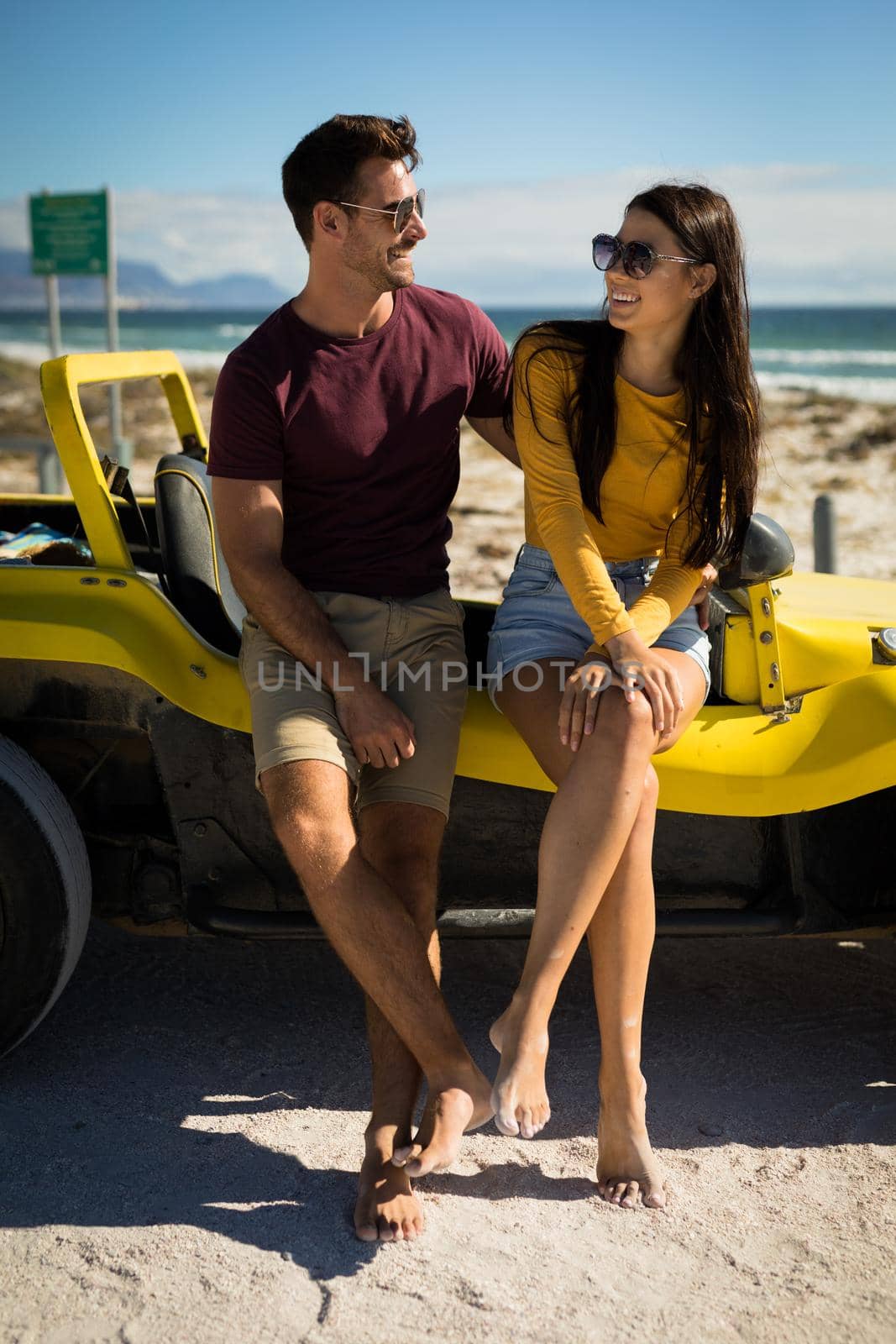 Happy caucasian couple sitting on beach buggy by the sea embracing by Wavebreakmedia