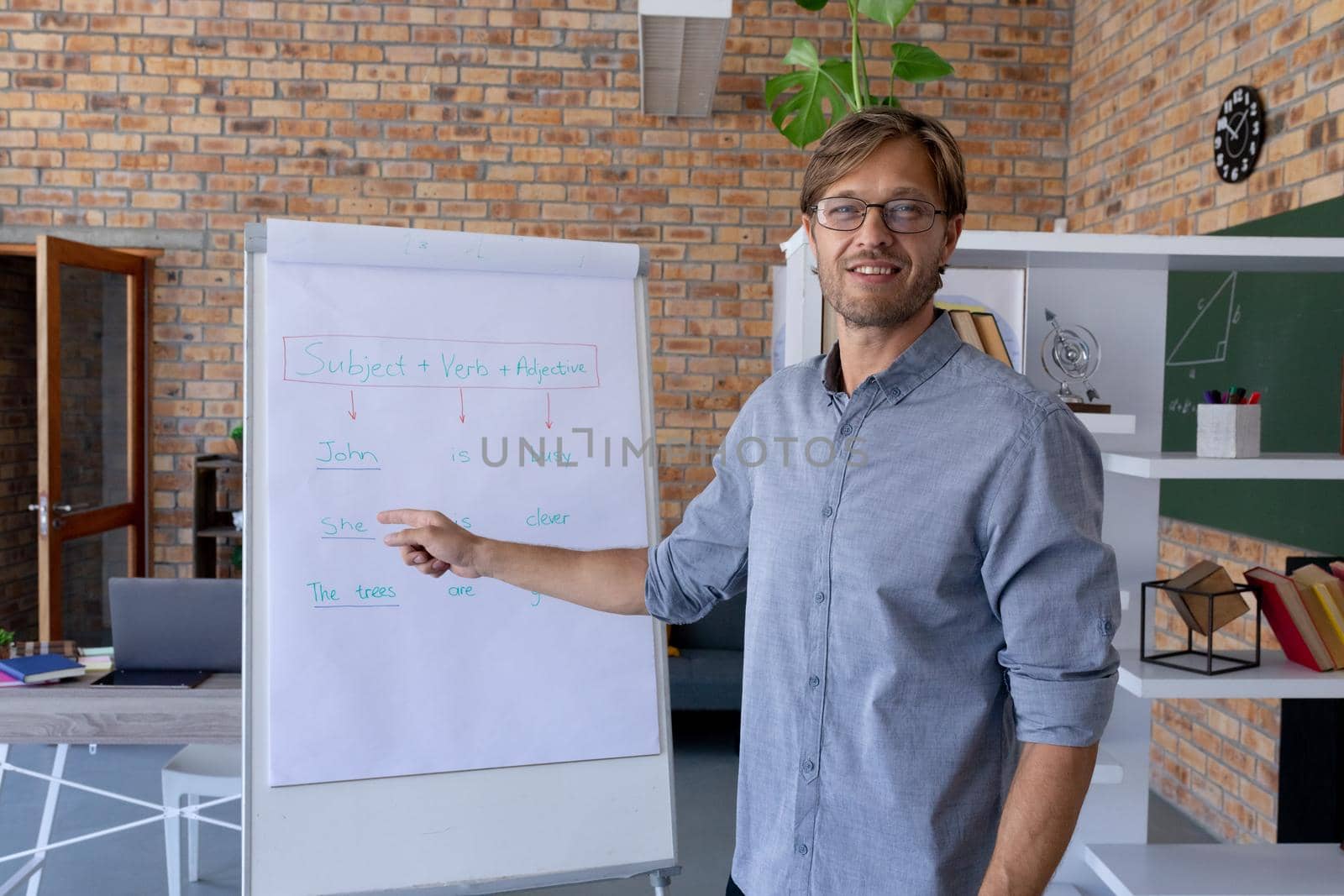 Caucasian male english teacher giving online lesson standing smiling using easel pad. home schooling and online education during quarantine lockdown.
