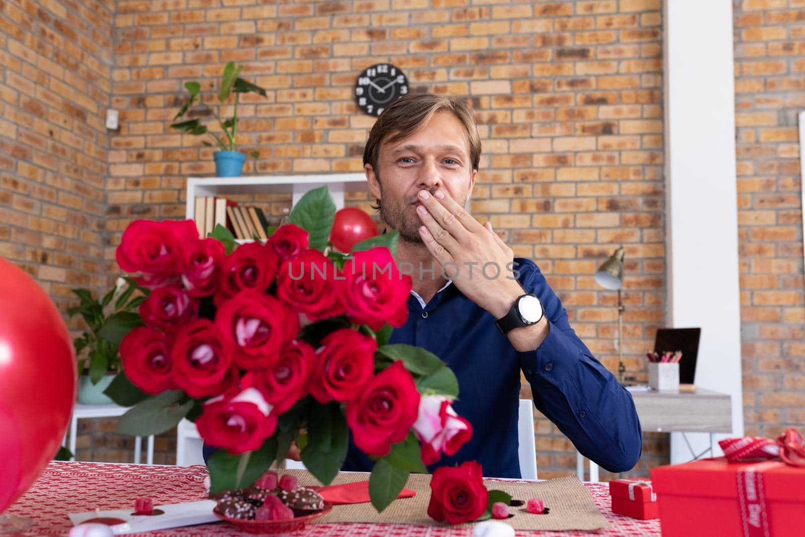 Caucasian man making video call holding bunch of red roses and blowing a kiss by Wavebreakmedia