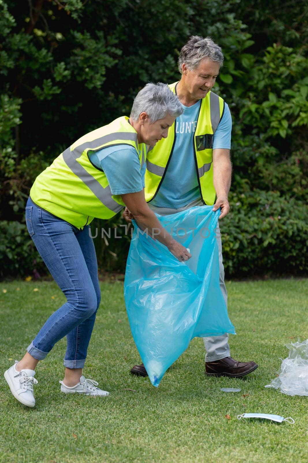 Caucasian senior couple volunteers holding refuse sack collecting rubbish in field by Wavebreakmedia