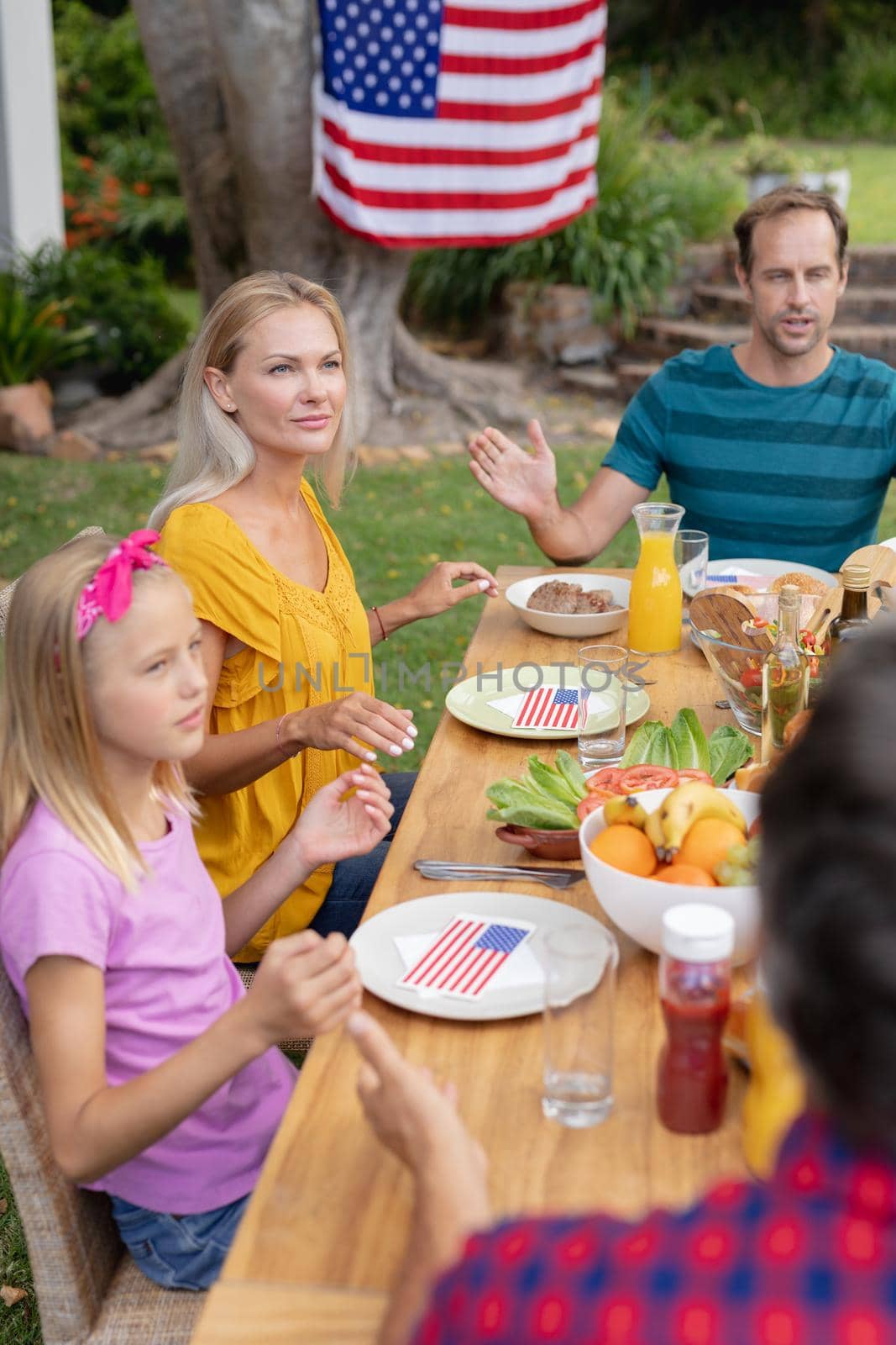 Caucasian man saying grace with family before eating meal together in garden by Wavebreakmedia