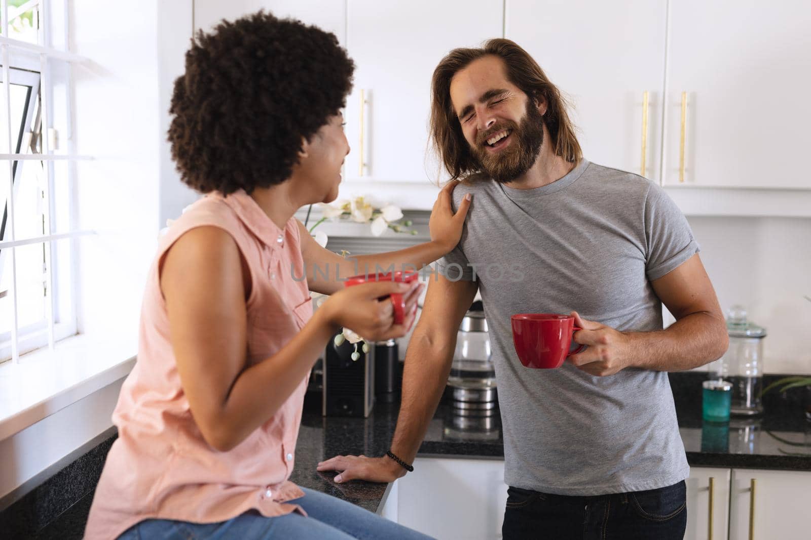 Happy diverse couple in kitchen drinking coffee and smiling by Wavebreakmedia