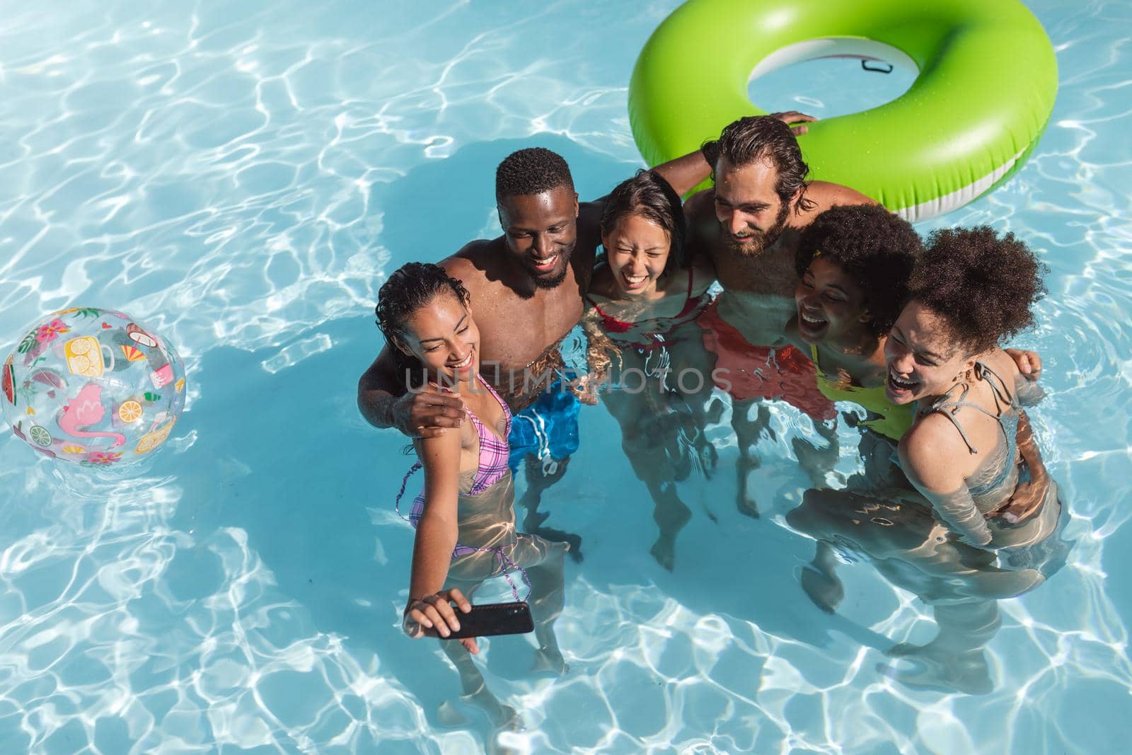 Diverse group of friends having fun and taking selfie in swimming pool by Wavebreakmedia