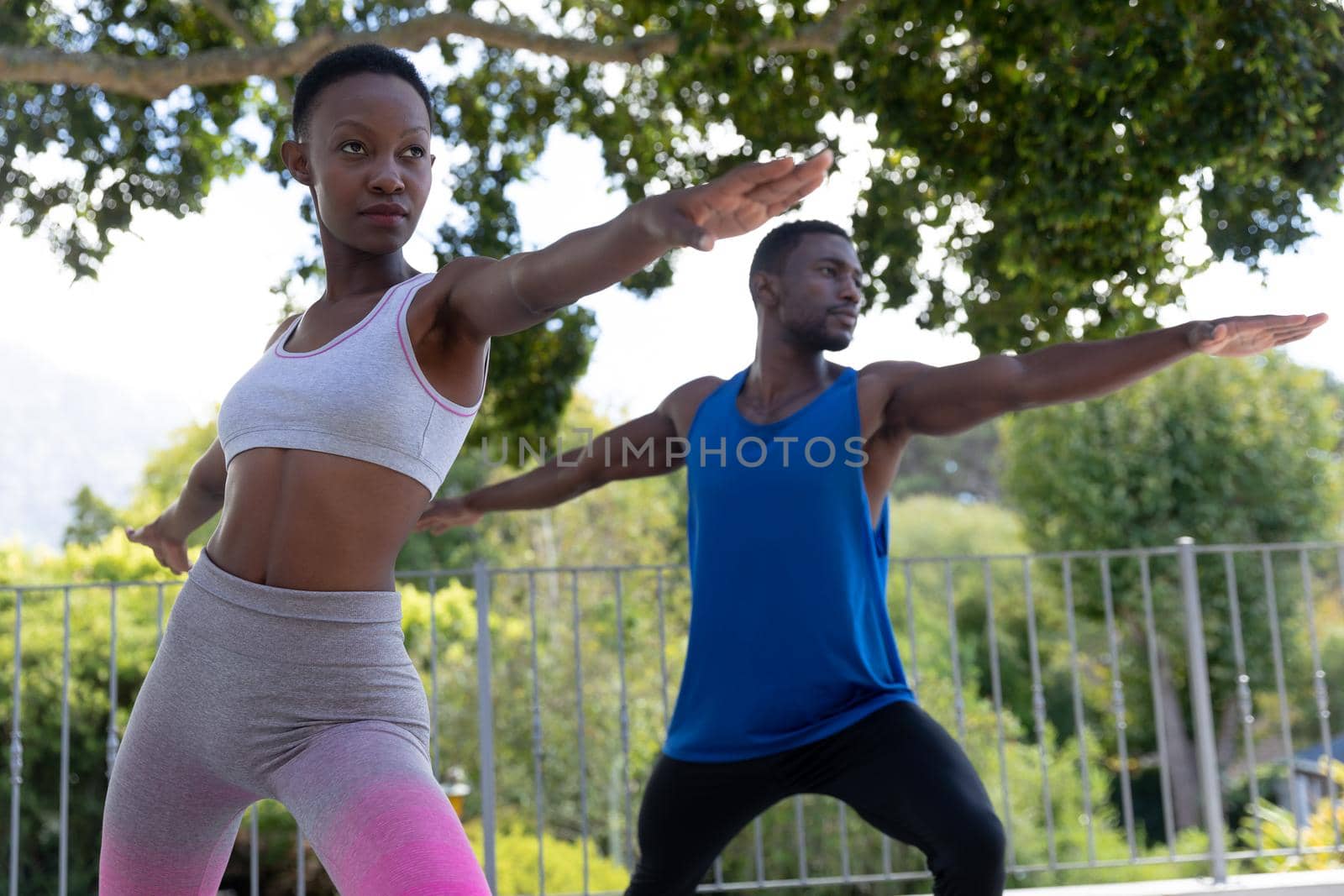 African american couple exercising practicing yoga on sunny garden terrace. staying at home in isolation during quarantine lockdown.