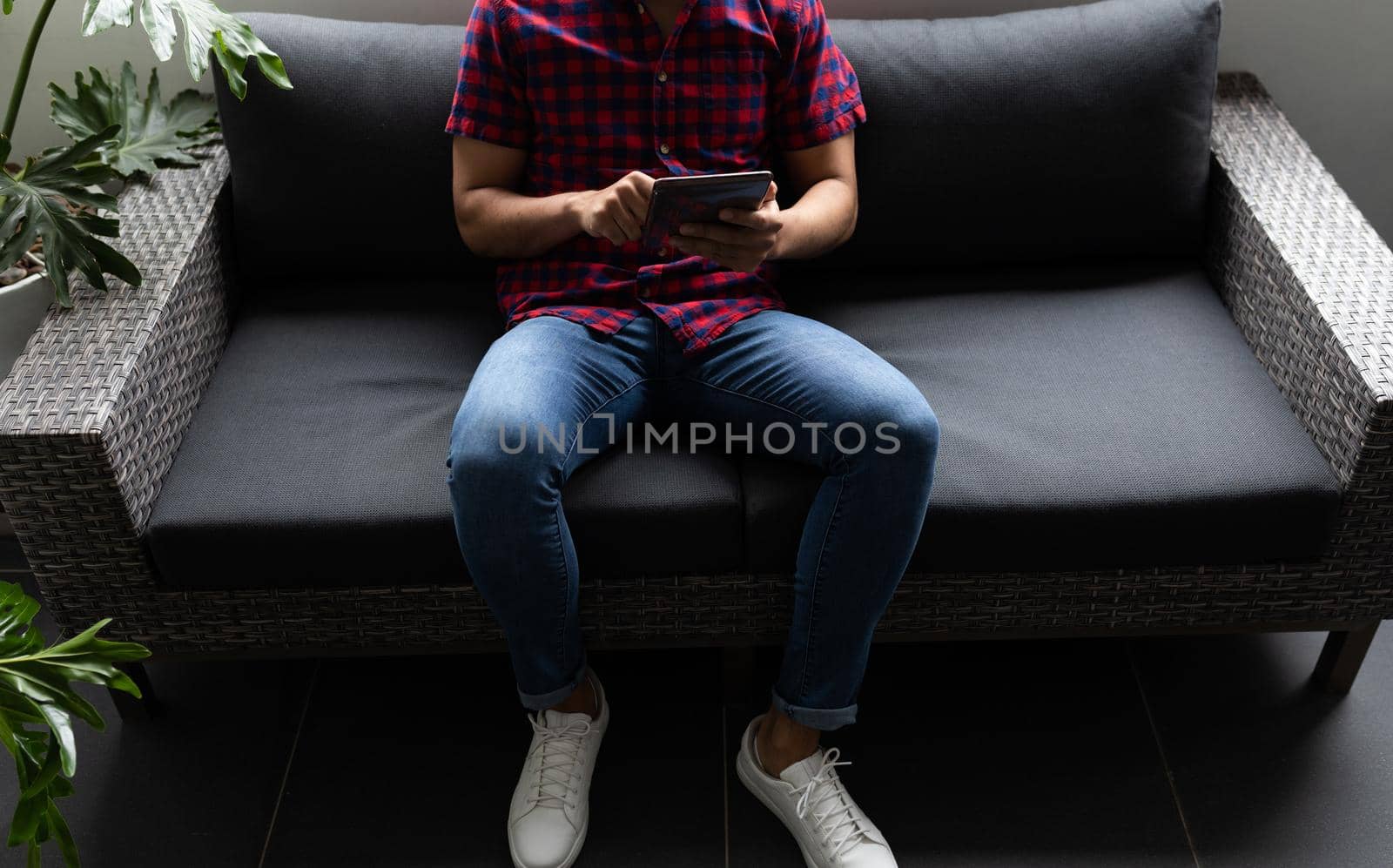 Mixed race businessman working in creative office. man sitting and using tablet. social distancing in workplace during covid 19 pandemic.