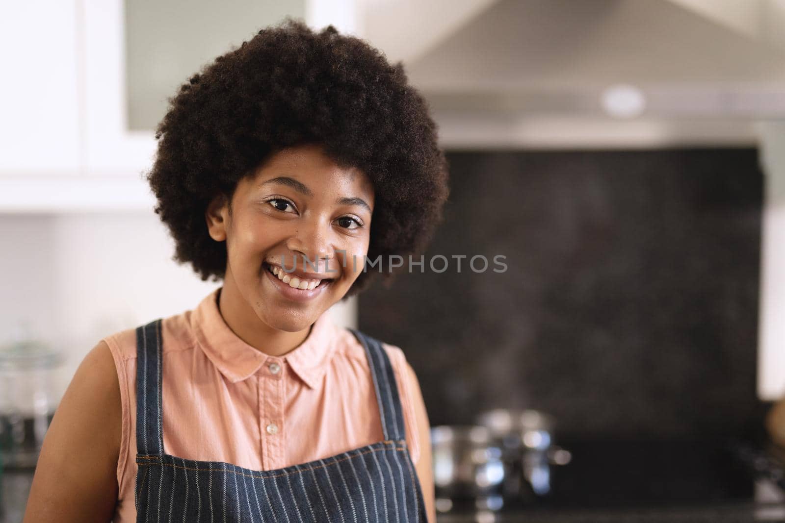 Portrait of african american woman in kitchen looking at camera and smiling. staying at home in isolation during quarantine lockdown.