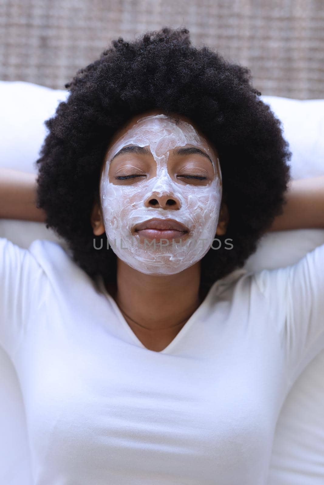African american woman lying in bed wearing beauty mask. staying at home in isolation during quarantine lockdown.