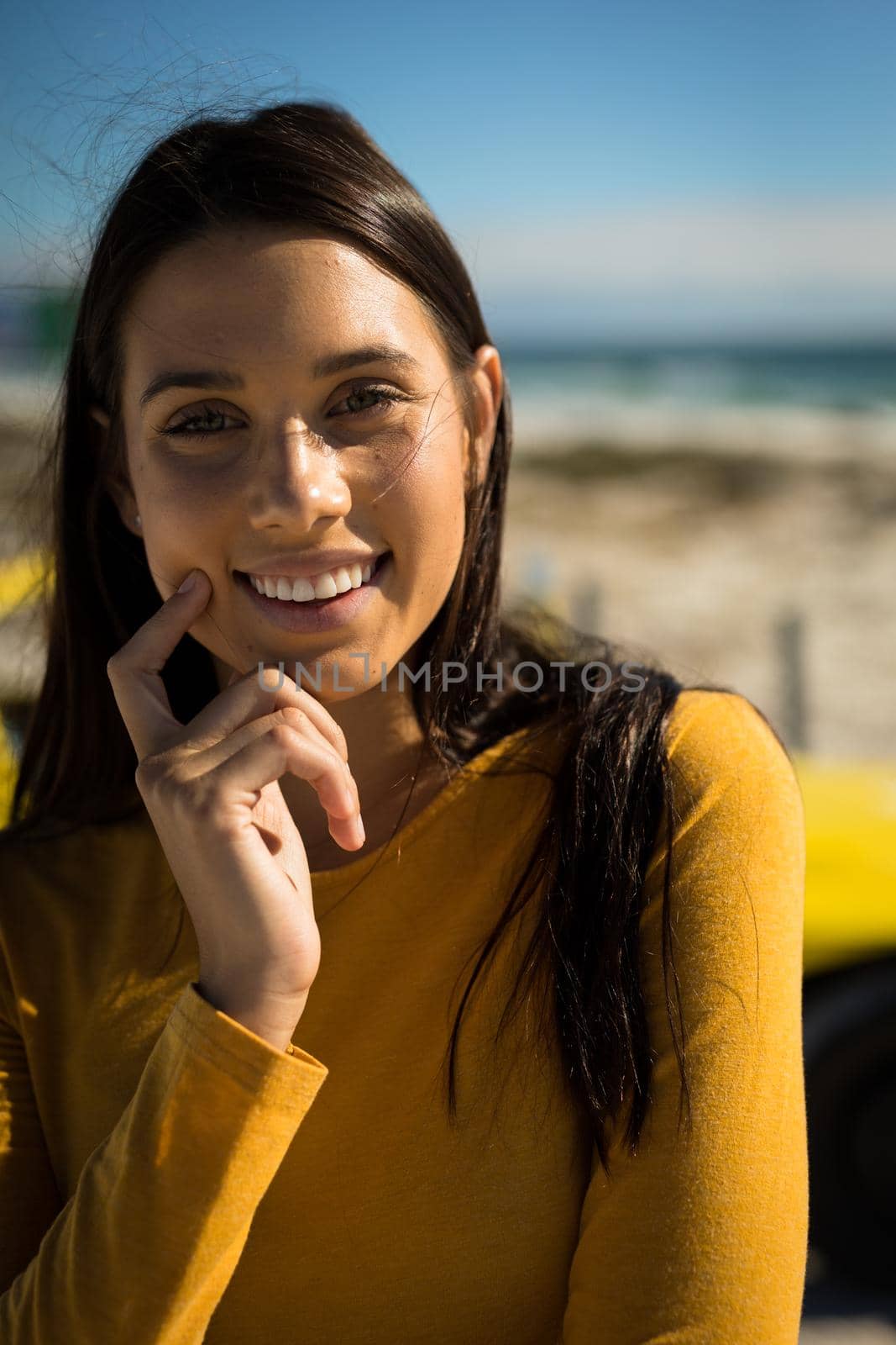 Portrait of happy caucasian woman on beach by the sea looking to camera. beach break on summer holiday road trip.