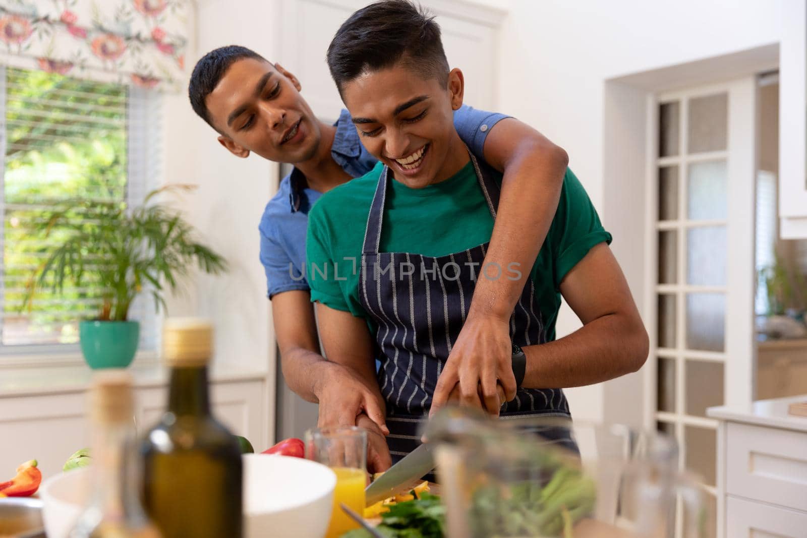 Diverse gay male couple spending time in kitchen cooking together and smiling by Wavebreakmedia